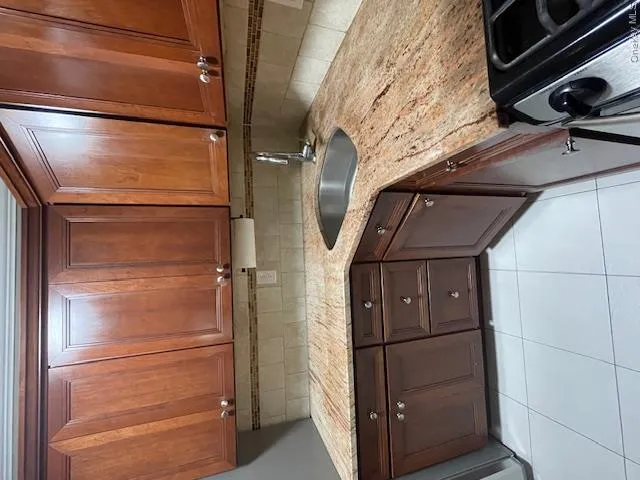 Kitchen with light stone countertops, tasteful backsplash, white range oven, light tile patterned flooring, and brown cabinetry Kitchen with light stone countertops, tasteful backsplash, white range oven, light tile patterned flooring, and brown cabinetry