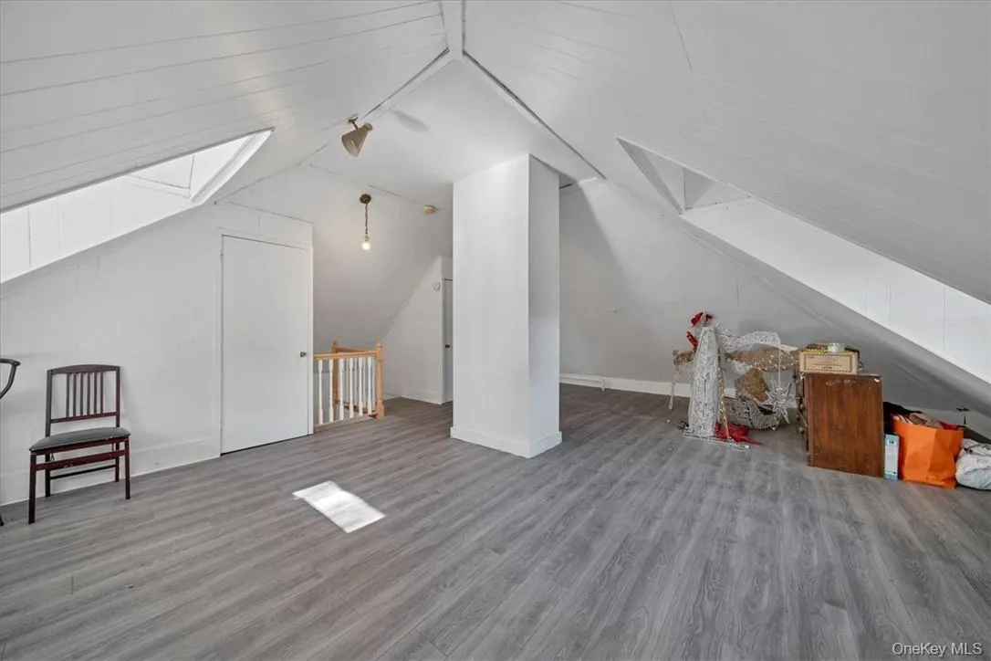 Additional living space with wood-type flooring and lofted ceiling with skylight Additional living space with wood-type flooring and lofted ceiling with skylight