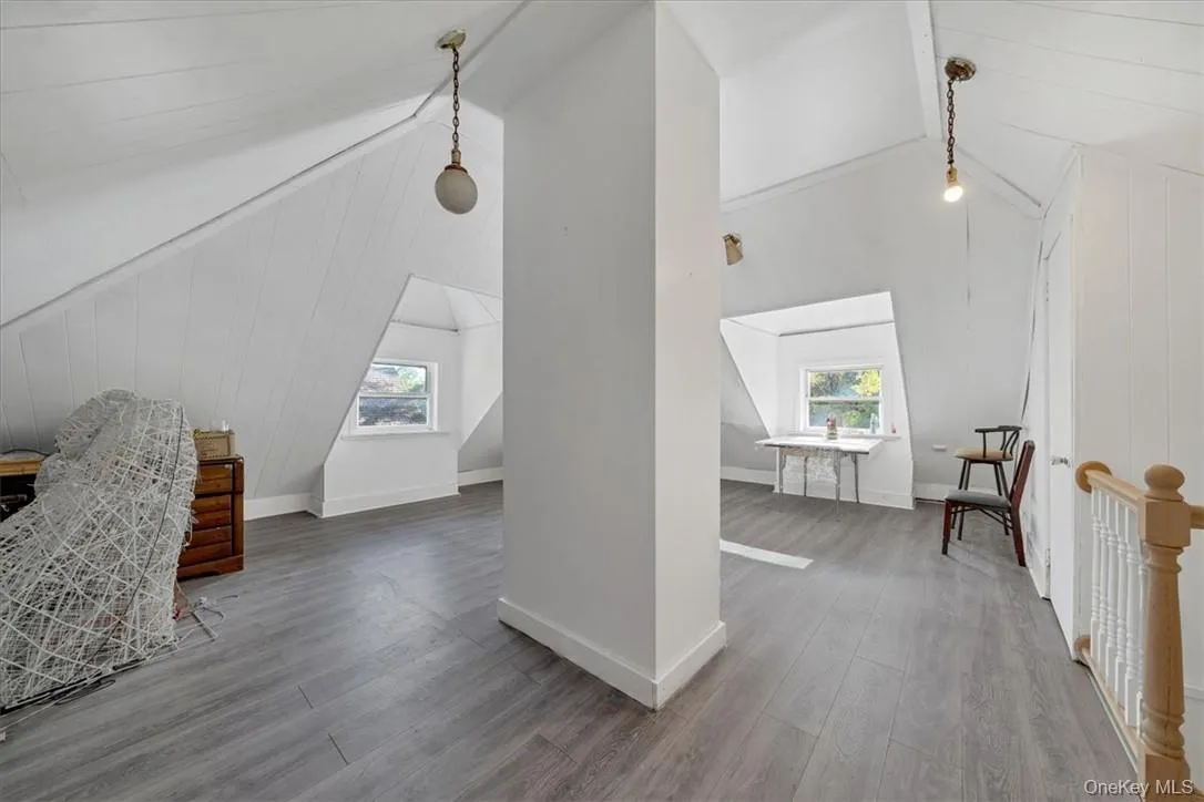 Bonus room featuring wood walls, wood-type flooring, beamed ceiling, and a healthy amount of sunlight Bonus room featuring wood walls, wood-type flooring, beamed ceiling, and a healthy amount of sunlight