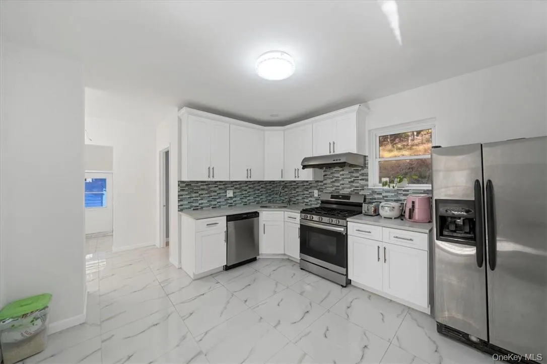 Kitchen featuring appliances with stainless steel finishes, white cabinetry, sink, and tasteful backsplash Kitchen featuring appliances with stainless steel finishes, white cabinetry, sink, and tasteful backsplash