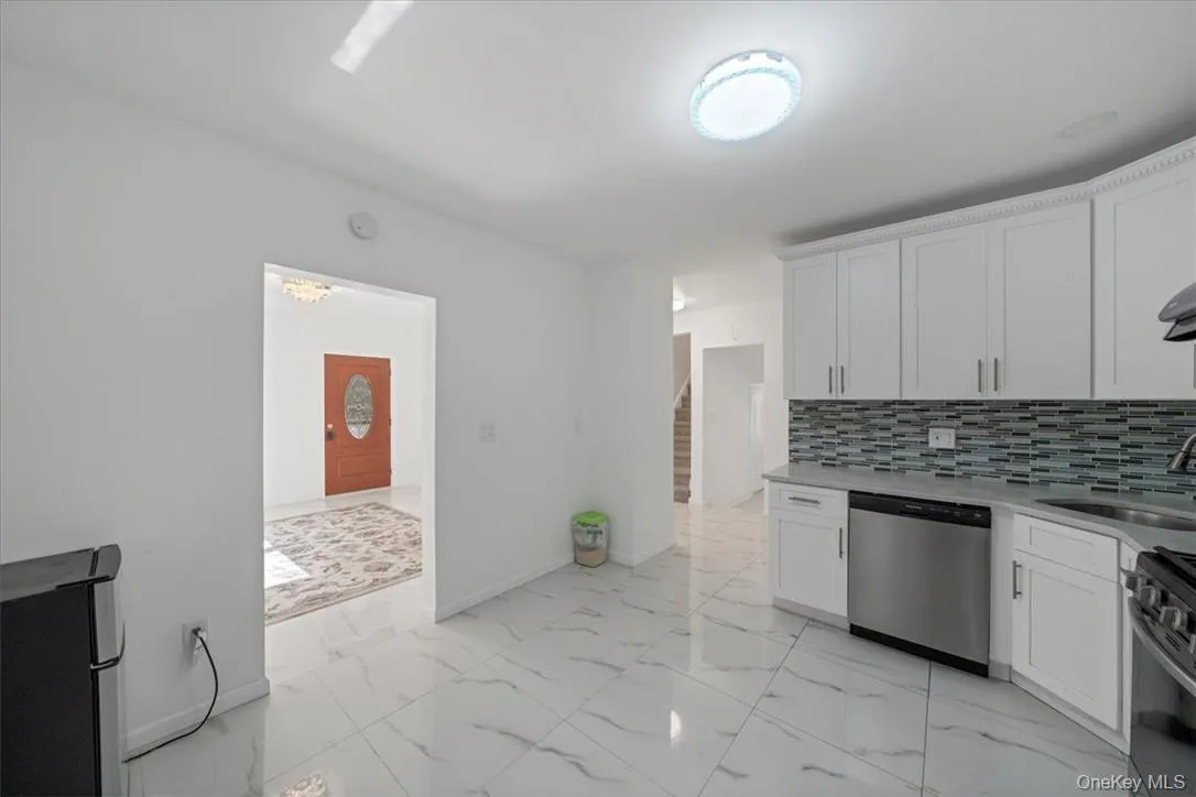 Kitchen featuring backsplash, appliances with stainless steel finishes, sink, and white cabinetry Kitchen featuring backsplash, appliances with stainless steel finishes, sink, and white cabinetry