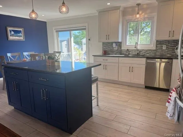 Modern kitchen with a dark blue island featuring cabinet storage and a dark countertop heated floors Modern kitchen with a dark blue island featuring cabinet storage and a dark countertop heated floors