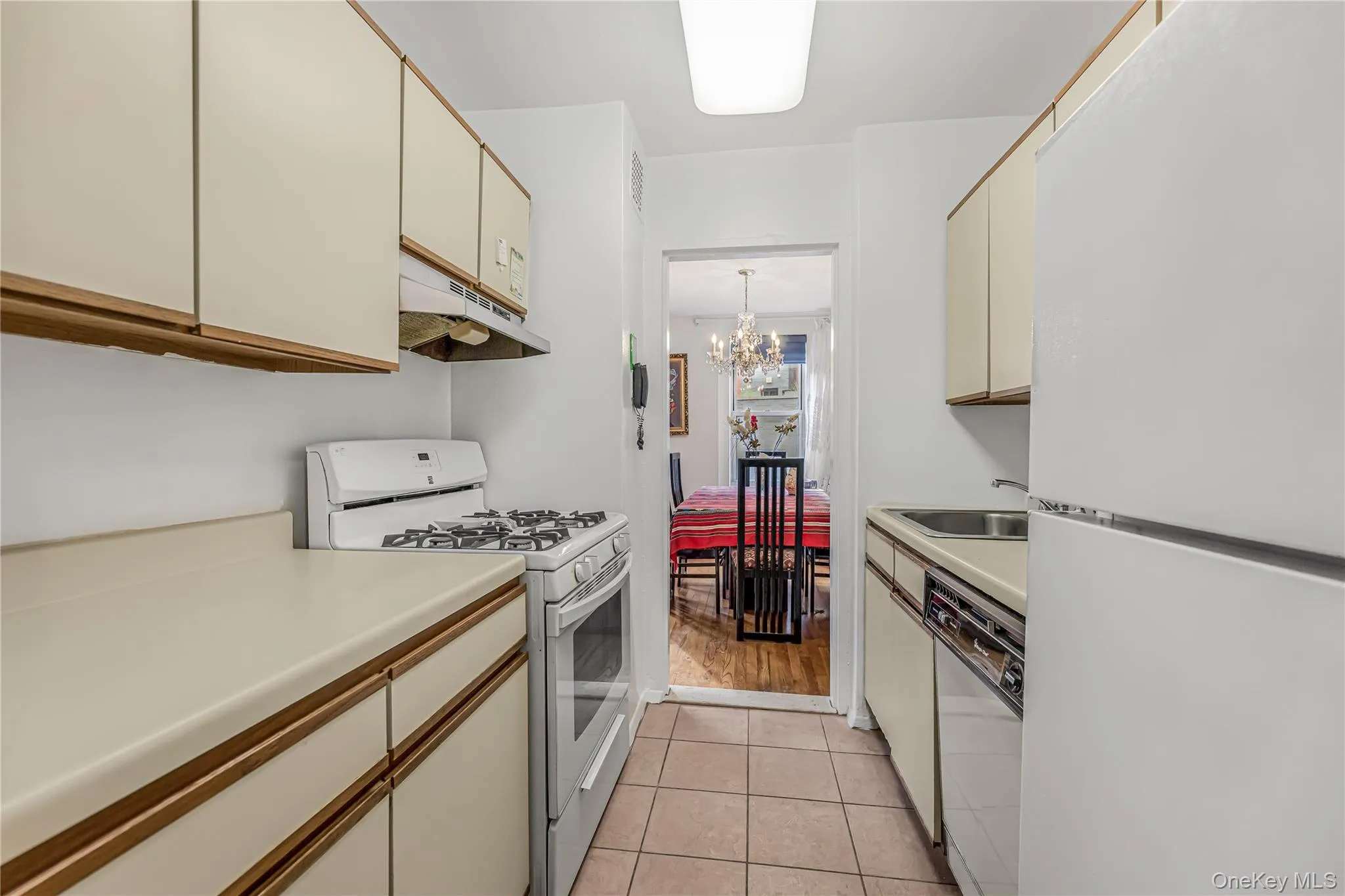 Galley kitchen featuring a gas range, white appliances, and ample cabinetry Galley kitchen featuring a gas range, white appliances, and ample cabinetry