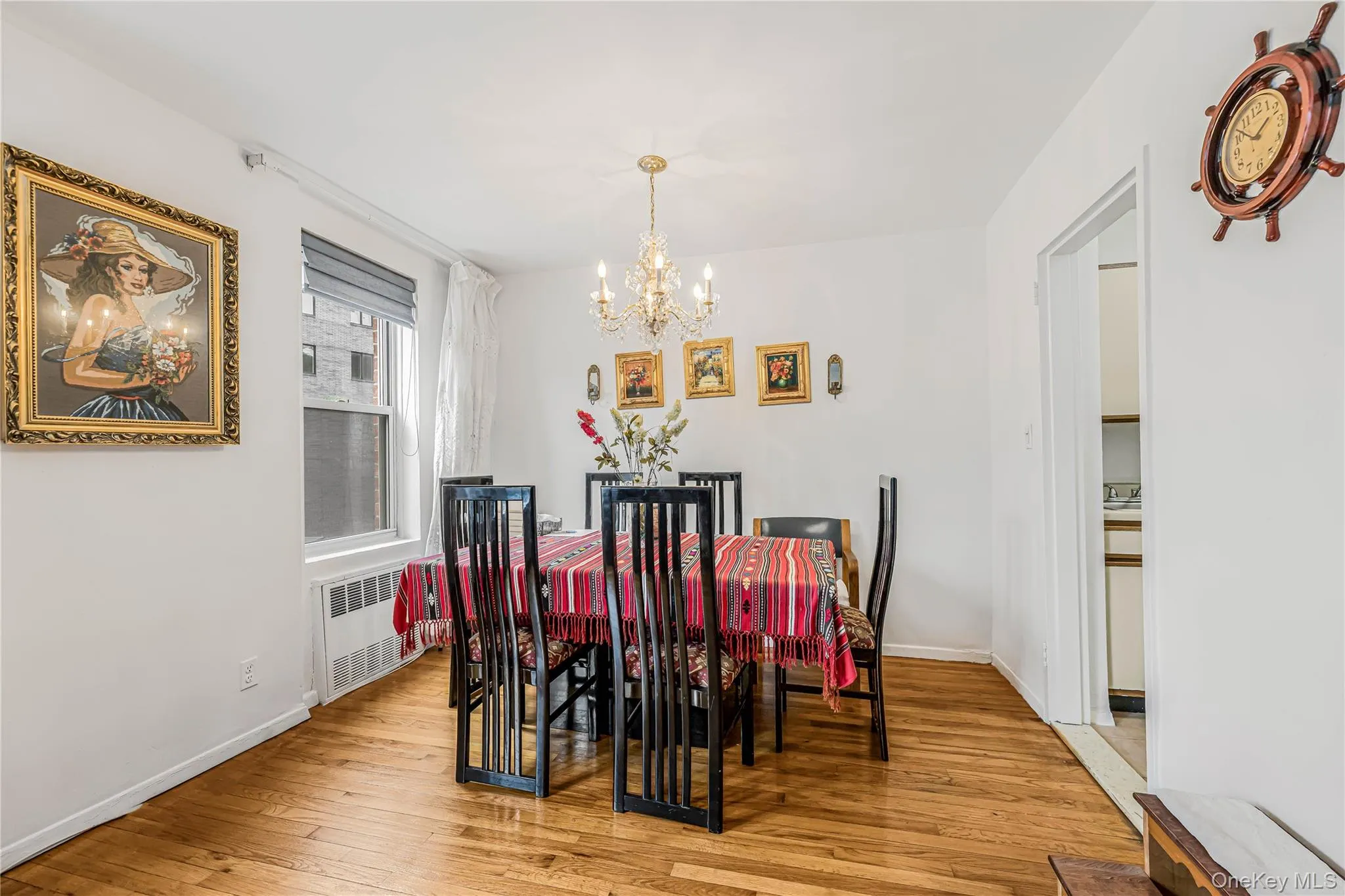 Dining area featuring wood-finish flooring, a contemporary chandelier, and a window with blinds Dining area featuring wood-finish flooring, a contemporary chandelier, and a window with blinds