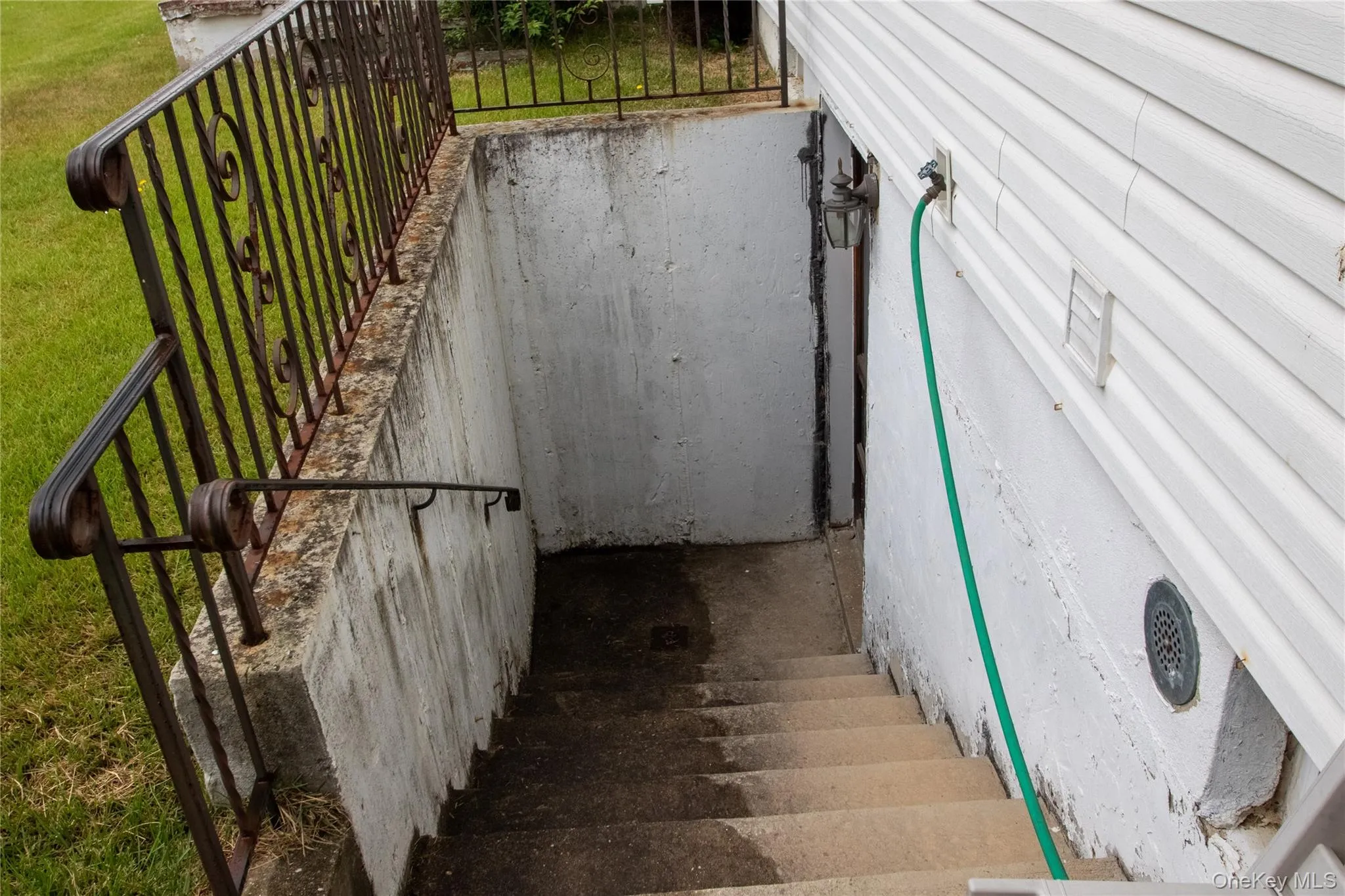 Exterior access stairway featuring concrete steps and a wrought iron railing Exterior access stairway featuring concrete steps and a wrought iron railing