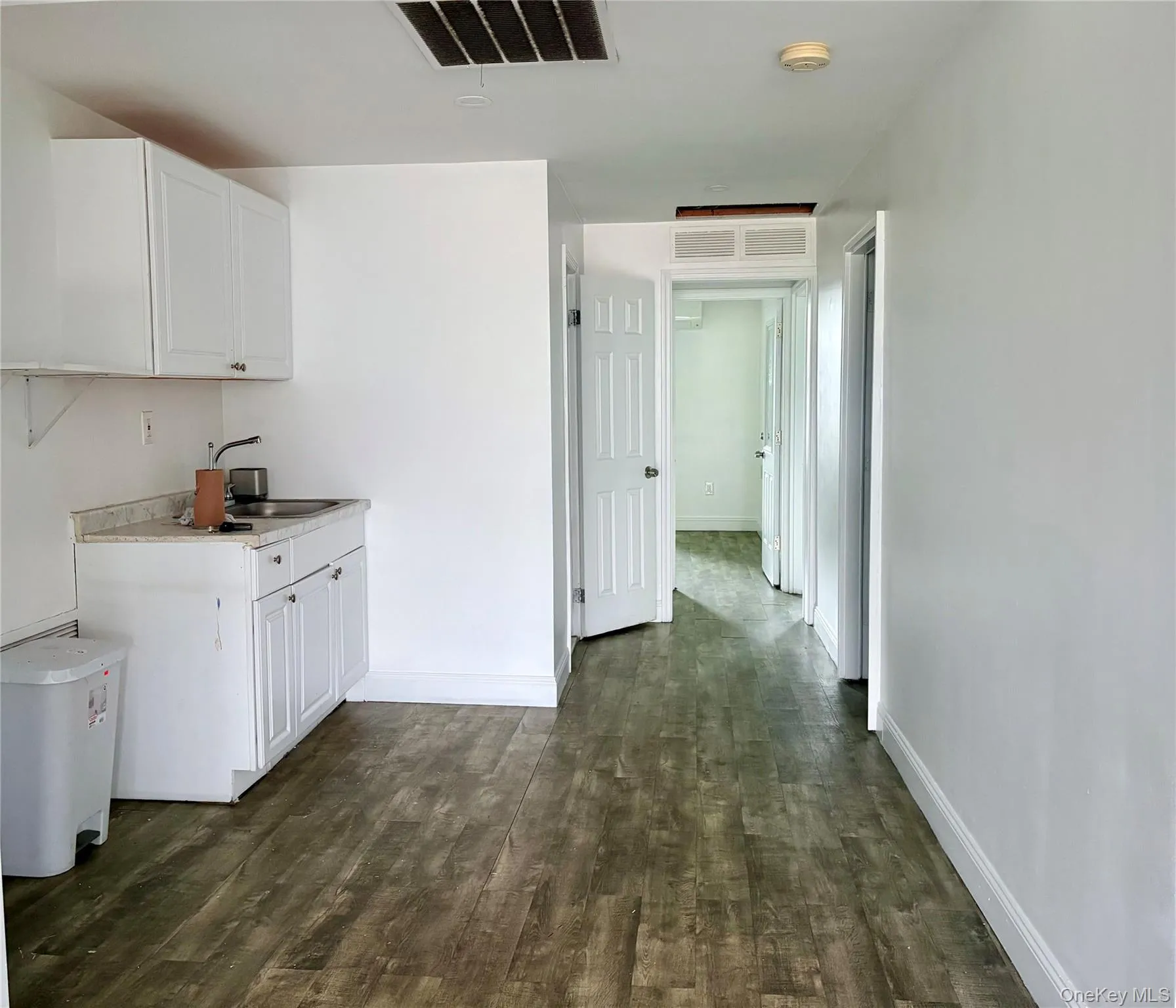 Convenient kitchenette area featuring a sink, storage cabinetry, and access to multiple private rooms, ideal for office, professional, or administrative use. Convenient kitchenette area featuring a sink, storage cabinetry, and access to multiple private rooms, ideal for office, professional, or administrative use.
