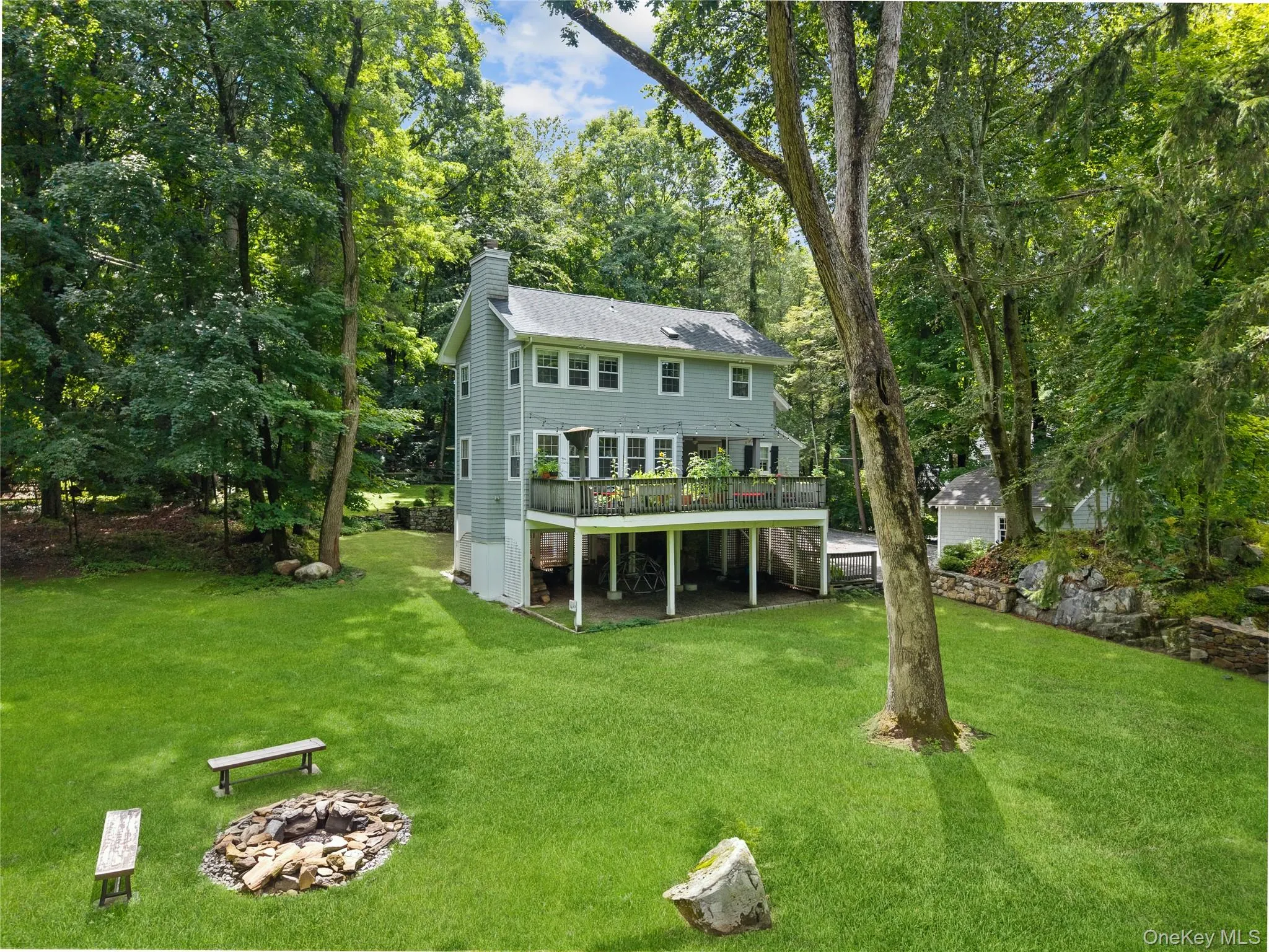 Expansive green lawn surrounded by mature trees, protected by green space and featuring a raised deck. Expansive green lawn surrounded by mature trees, protected by green space and featuring a raised deck.