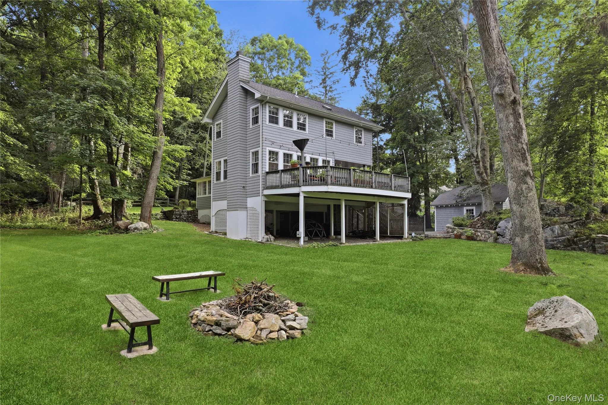 Expansive green lawn surrounded by mature trees, protected by green space and featuring a raised deck. Expansive green lawn surrounded by mature trees, protected by green space and featuring a raised deck.