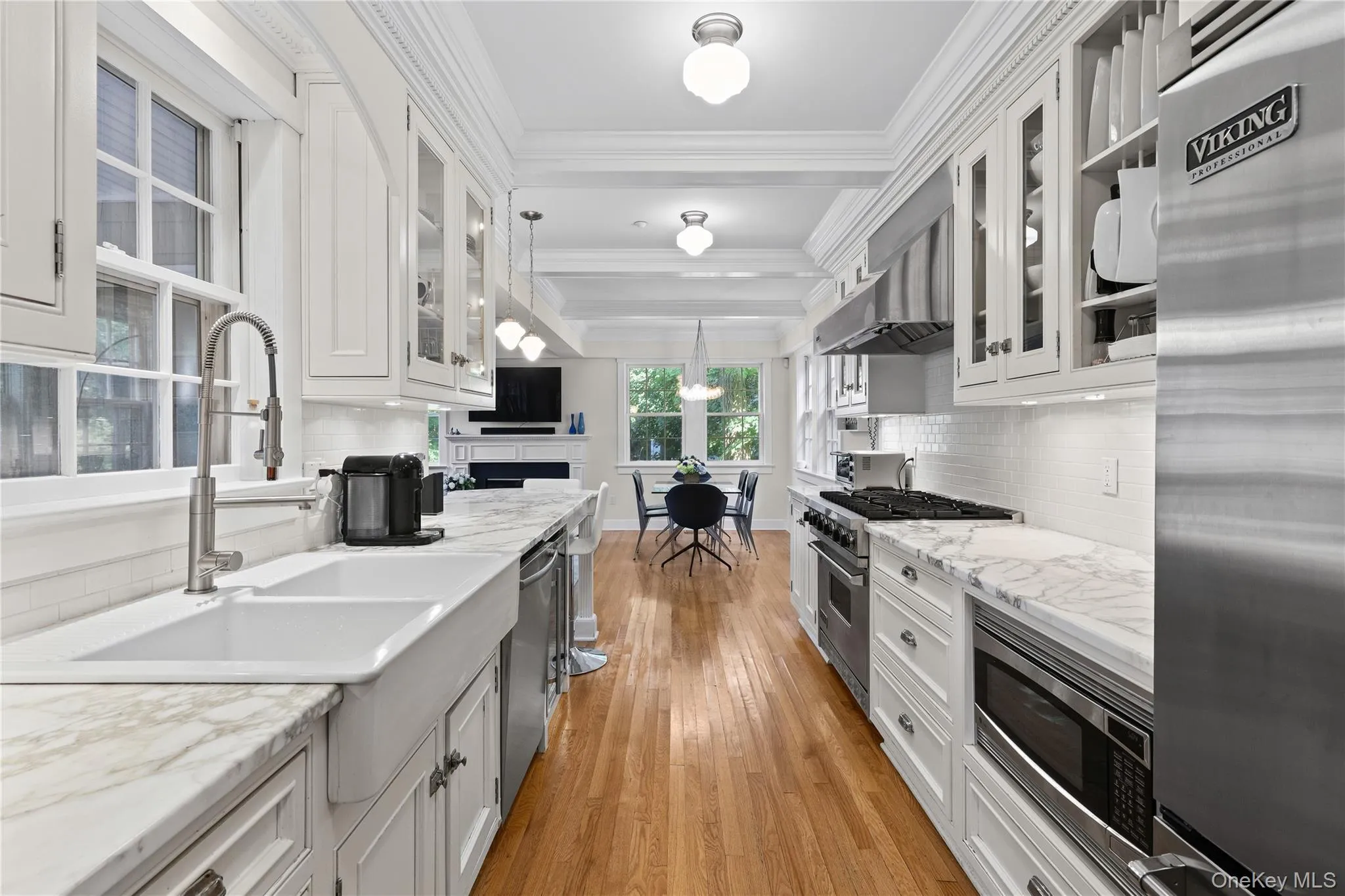 Kitchen featuring hardwood flooring, custom cabinetry, Wolf stainless steel appliances, marble counter tops, white subway tile backsplash, and a breakfast bar. Kitchen featuring hardwood flooring, custom cabinetry, Wolf stainless steel appliances, marble counter tops, white subway tile backsplash, and a breakfast bar.