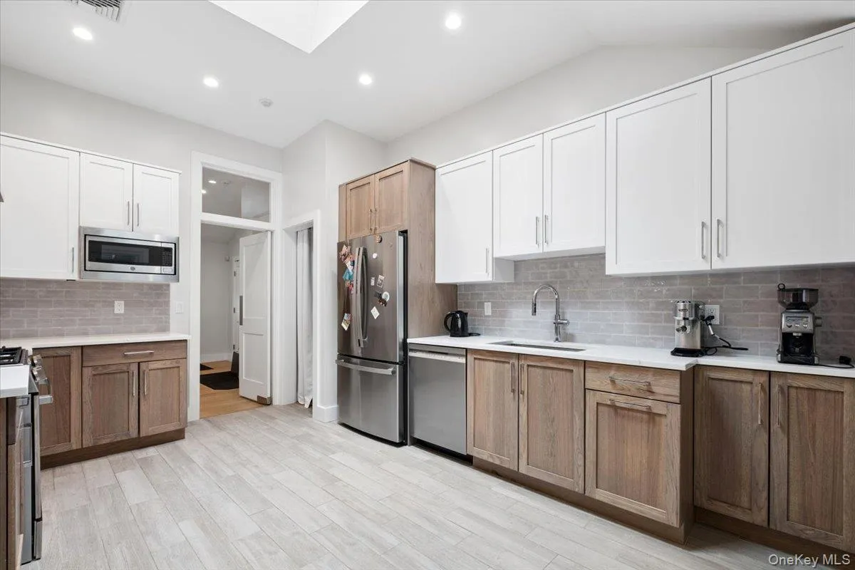 Kitchen featuring high-end tile, white upper cabinetry, and contrasting natural wood-finish lower cabinetry Kitchen featuring high-end tile, white upper cabinetry, and contrasting natural wood-finish lower cabinetry