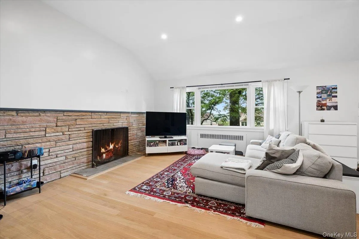 Living area featuring a natural stone fireplace with a hearth, hard wood flooring, and recessed lighting Living area featuring a natural stone fireplace with a hearth, hard wood flooring, and recessed lighting
