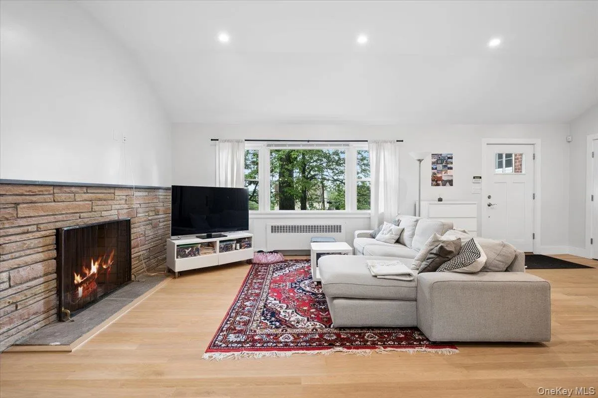Living area featuring a stone-front fireplace with a stone hearth, recessed lighting, and a front entry door with transom lites Living area featuring a stone-front fireplace with a stone hearth, recessed lighting, and a front entry door with transom lites