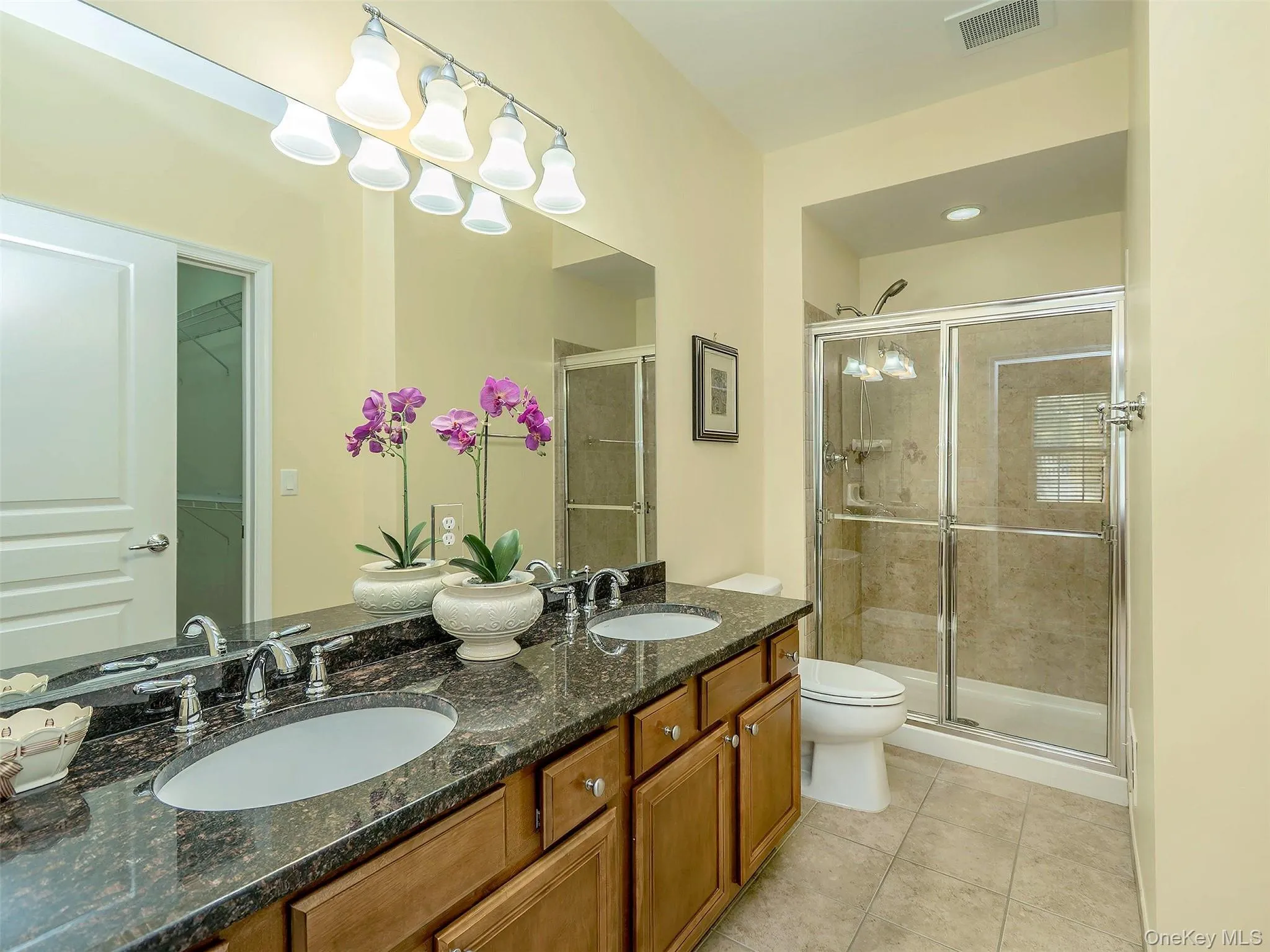 Bathroom featuring a double vanity with granite countertop, dual undermount sinks, chrome faucets, and large shower. Bathroom featuring a double vanity with granite countertop, dual undermount sinks, chrome faucets, and large shower.