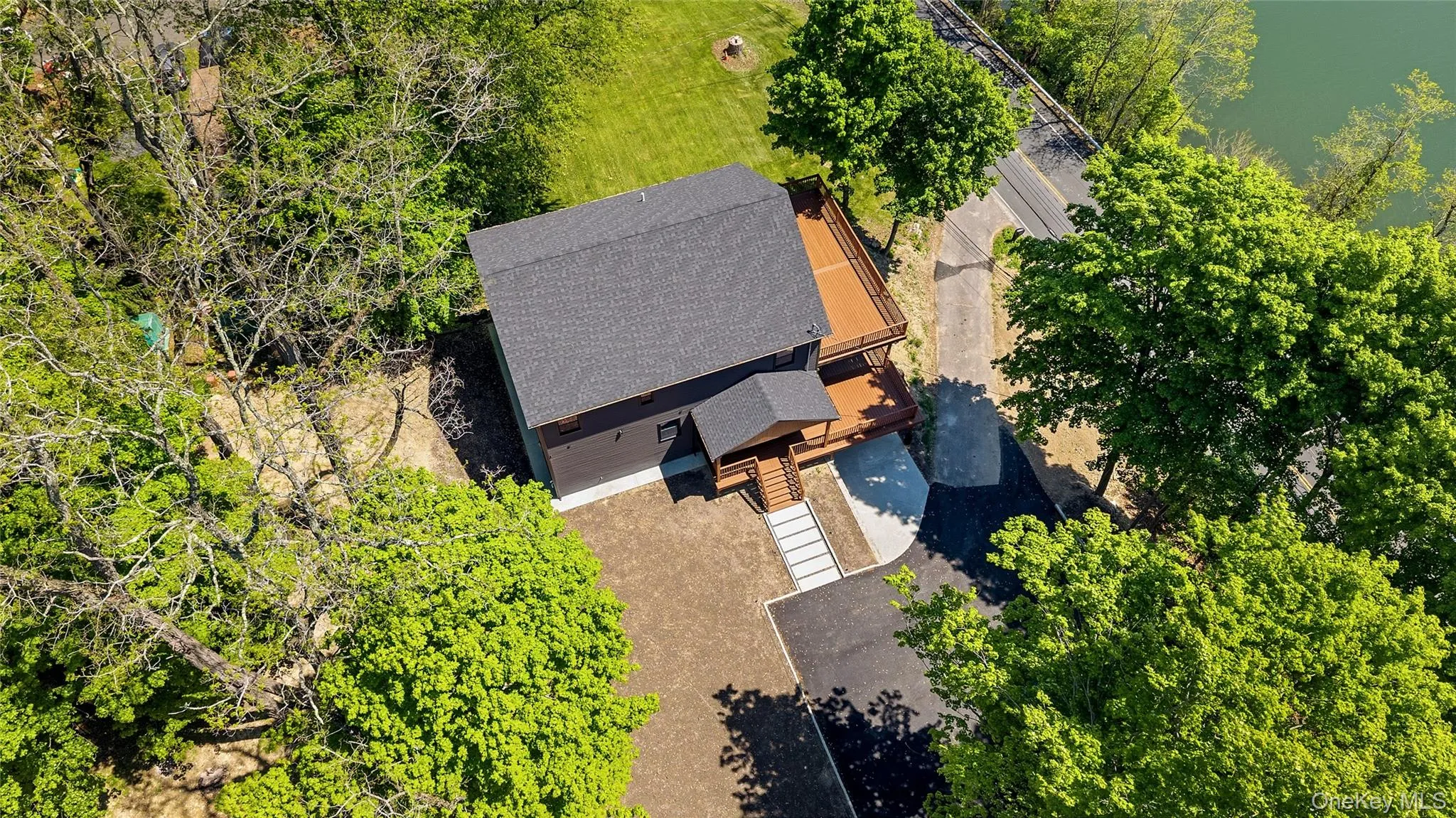 Newly constructed property featuring a dark shingle roof, dark exterior siding, and a prominent wood-finish deck Newly constructed property featuring a dark shingle roof, dark exterior siding, and a prominent wood-finish deck