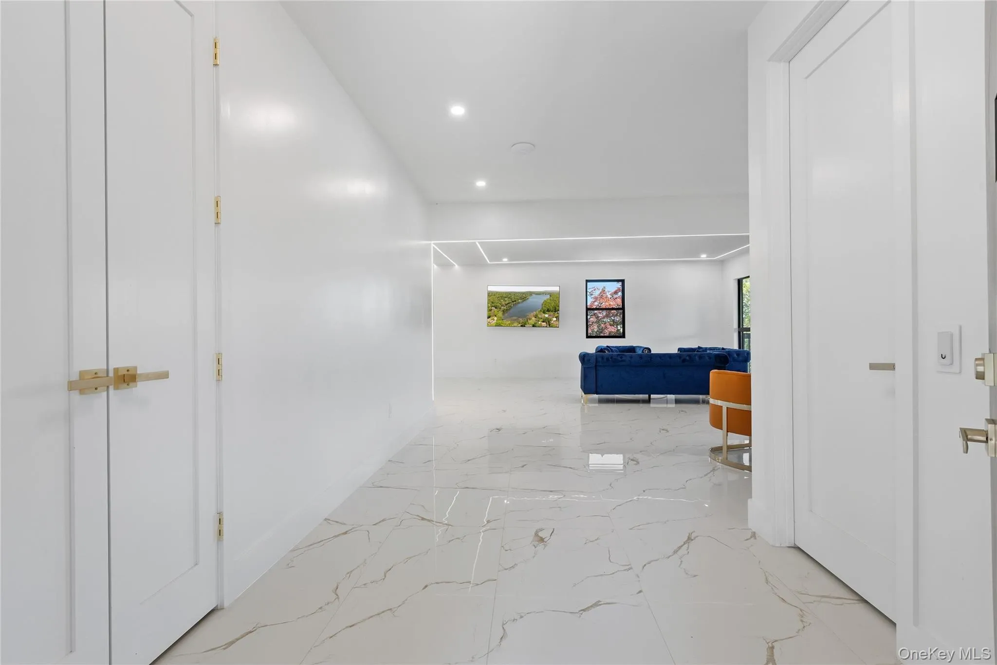 Hallway featuring marble-look flooring, recessed lighting, and white panel doors with brass hardware Hallway featuring marble-look flooring, recessed lighting, and white panel doors with brass hardware