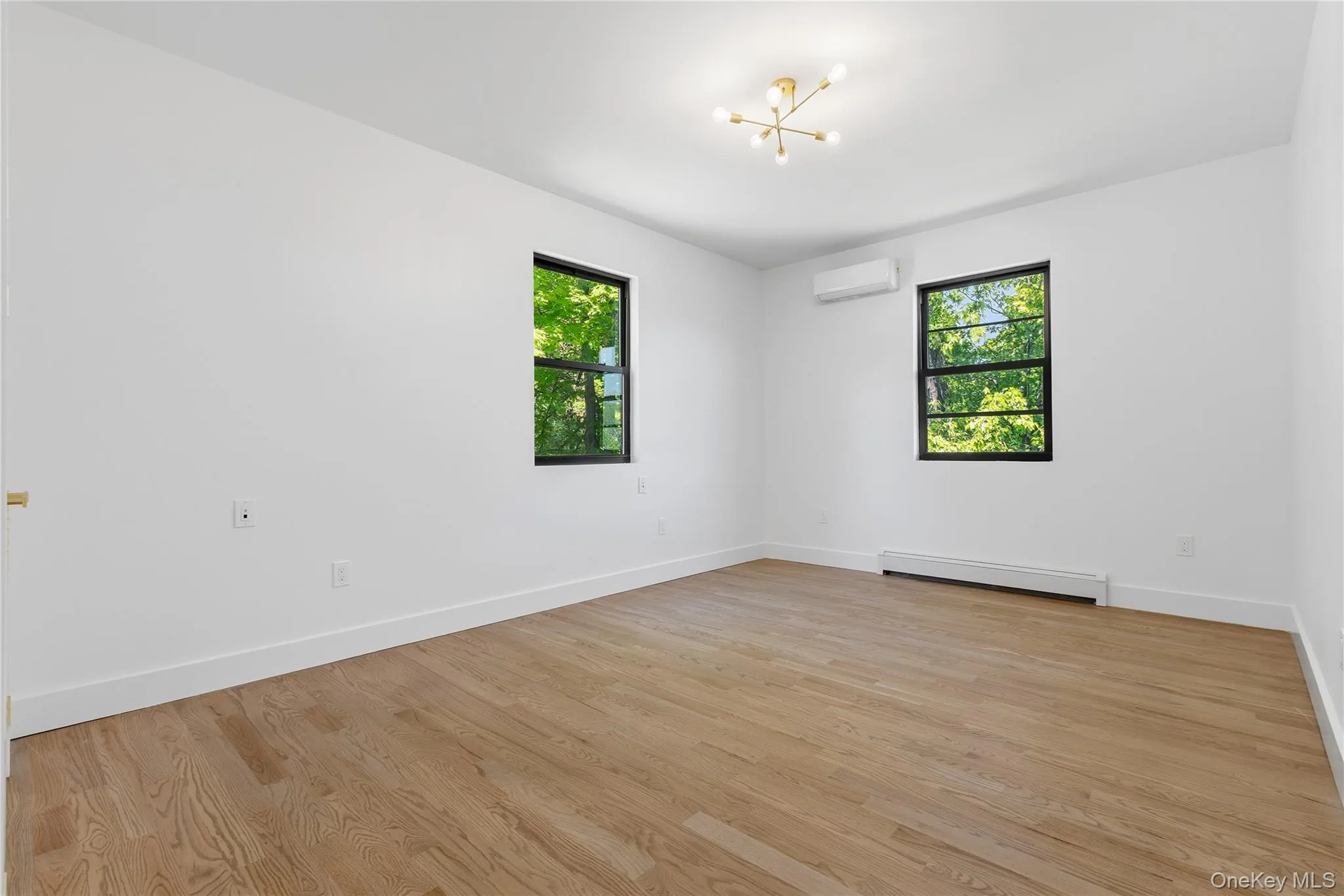 Bright room featuring light wood-finish flooring, white walls, and white baseboards Bright room featuring light wood-finish flooring, white walls, and white baseboards