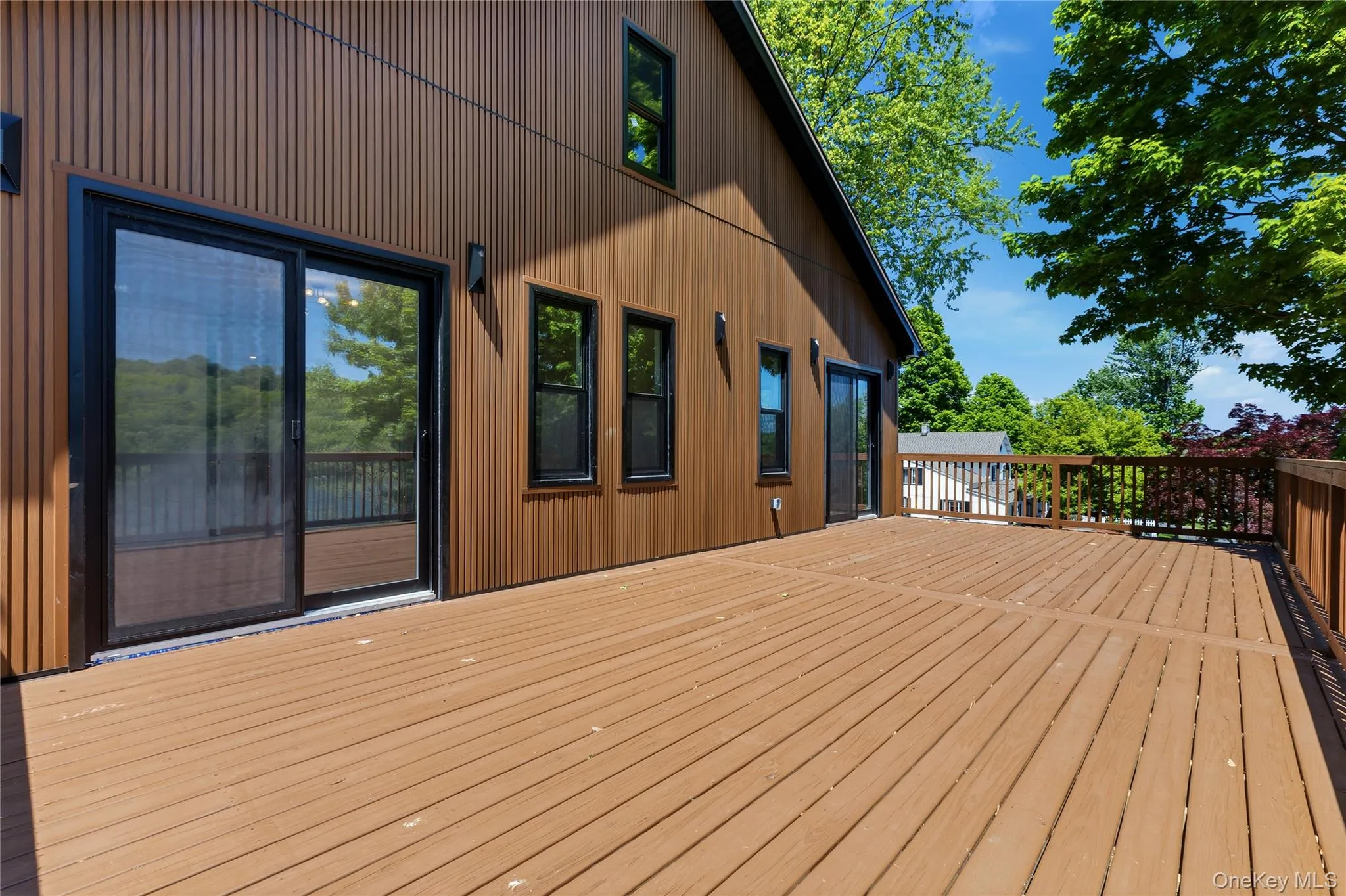 Spacious outdoor deck featuring natural wood-finish planks and matching wood railings Spacious outdoor deck featuring natural wood-finish planks and matching wood railings