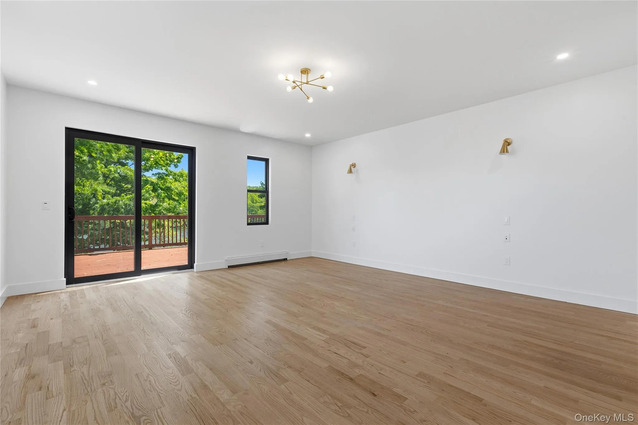 Expansive room featuring light wood-finish flooring and a contemporary chandelier Expansive room featuring light wood-finish flooring and a contemporary chandelier