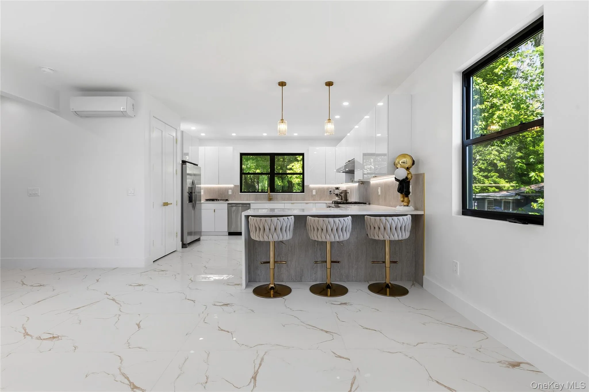 Open-concept kitchen and living area featuring marble-look tile flooring, white shaker cabinetry, stainless steel appliances, and a kitchen island with seating Open-concept kitchen and living area featuring marble-look tile flooring, white shaker cabinetry, stainless steel appliances, and a kitchen island with seating