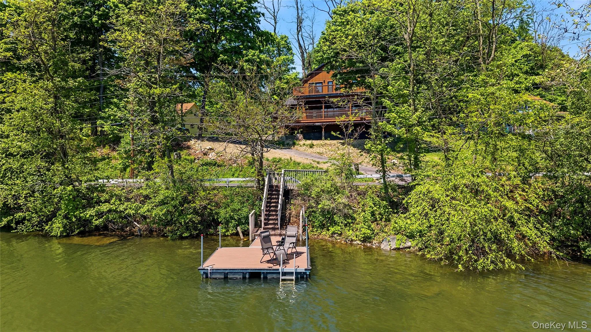 Waterfront property featuring a private dock with integrated ladder, a multi-level deck, and a wood-sided structure Waterfront property featuring a private dock with integrated ladder, a multi-level deck, and a wood-sided structure