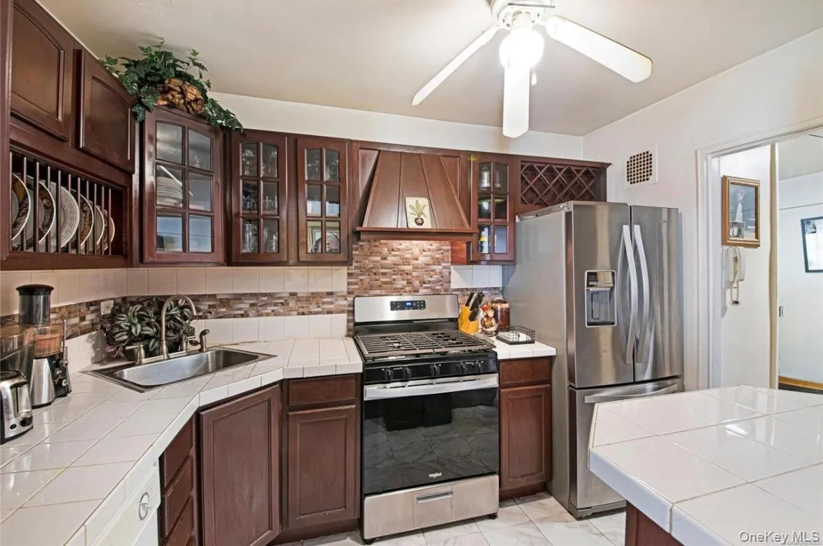 Kitchen featuring dark wood-finish cabinetry, a tile backsplash, and a white tile countertop Kitchen featuring dark wood-finish cabinetry, a tile backsplash, and a white tile countertop