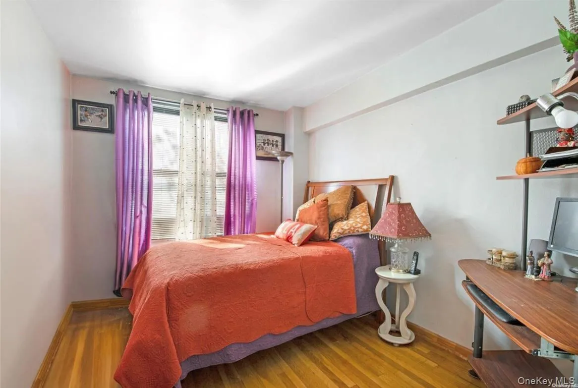 Hardwood flooring throughout featuring a window with vertical blinds and sheer curtains Hardwood flooring throughout featuring a window with vertical blinds and sheer curtains
