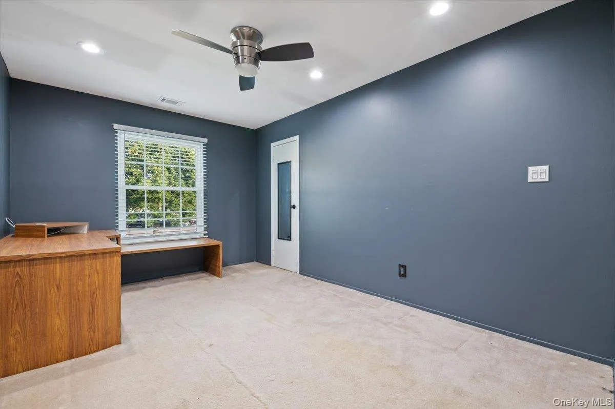 Room featuring a window with blinds, ceiling fan, recessed lighting, and built-in wood-finish desk Room featuring a window with blinds, ceiling fan, recessed lighting, and built-in wood-finish desk