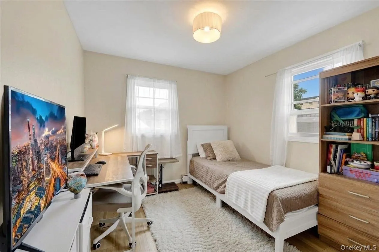 2nd bedroom featuring wood-finish flooring, a double-hung window with white trim, and a ceiling-mounted drum light fixture 2nd bedroom featuring wood-finish flooring, a double-hung window with white trim, and a ceiling-mounted drum light fixture