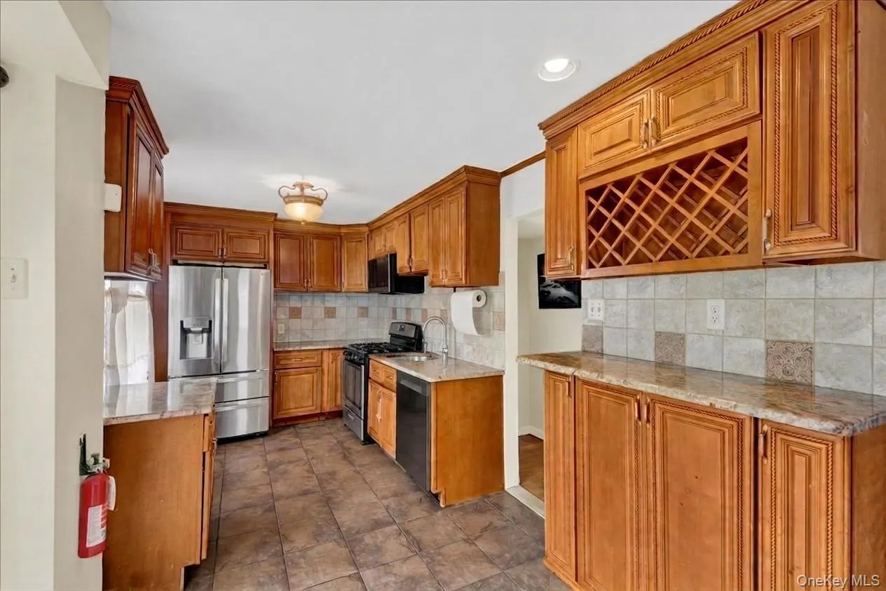 Kitchen featuring wood-finish cabinetry, granite-style countertops, and a full suite of stainless steel appliances Kitchen featuring wood-finish cabinetry, granite-style countertops, and a full suite of stainless steel appliances