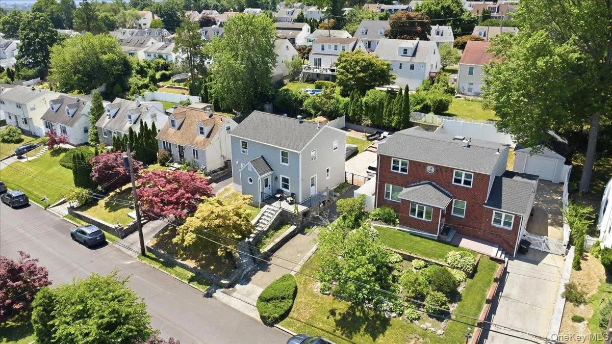 Residential street featuring a grey-sided property with a front entrance staircase, a brick property with multiple windows, and manicured lawns Residential street featuring a grey-sided property with a front entrance staircase, a brick property with multiple windows, and manicured lawns