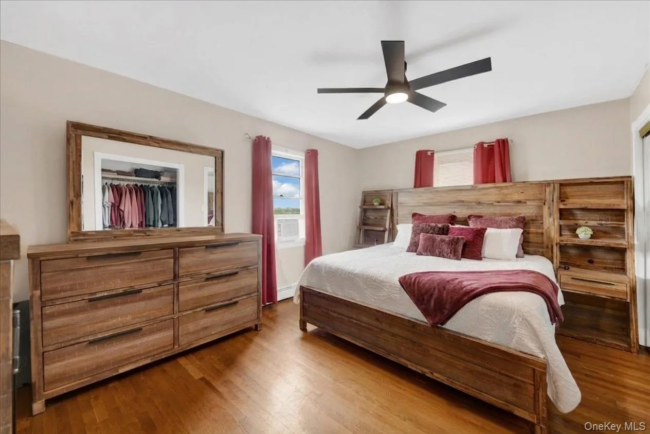 Spacious primary bedroom featuring wood-finish flooring and a contemporary ceiling fan Spacious primary bedroom featuring wood-finish flooring and a contemporary ceiling fan