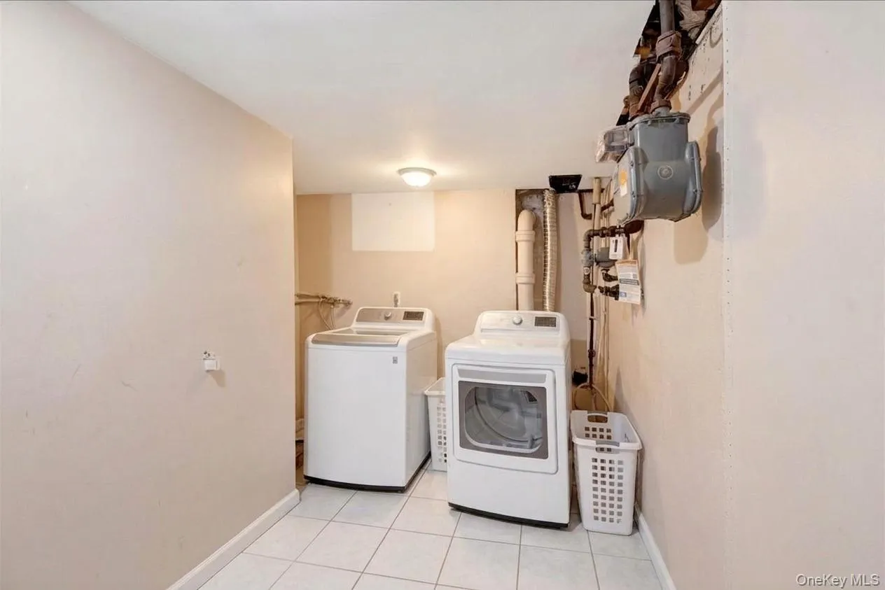 Dedicated laundry/utility room in basement featuring a washer and dryer, tile flooring, and overhead lighting Dedicated laundry/utility room in basement featuring a washer and dryer, tile flooring, and overhead lighting