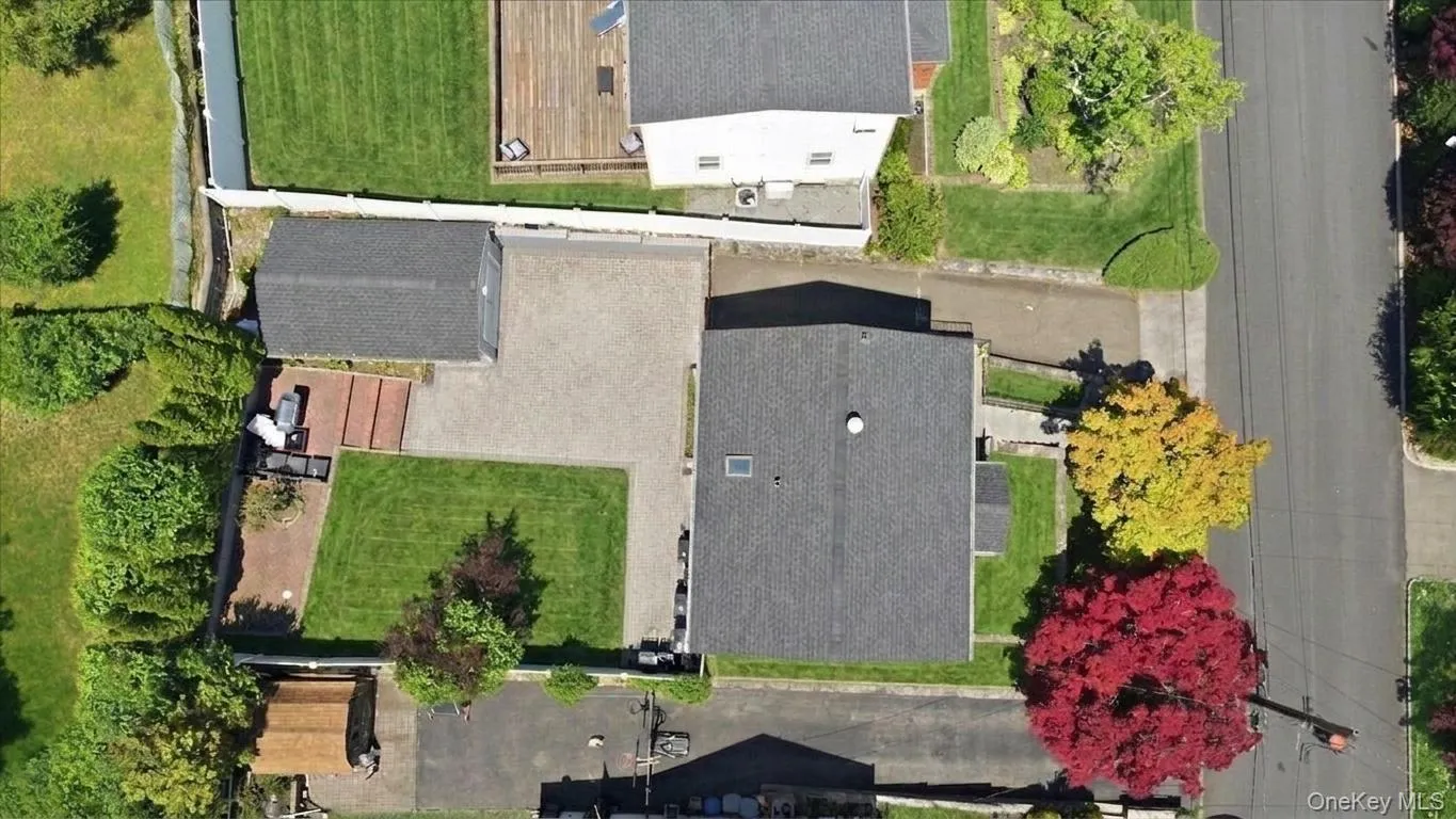 Property featuring a detached garage, expansive paver driveway, and a spacious green lawn Property featuring a detached garage, expansive paver driveway, and a spacious green lawn