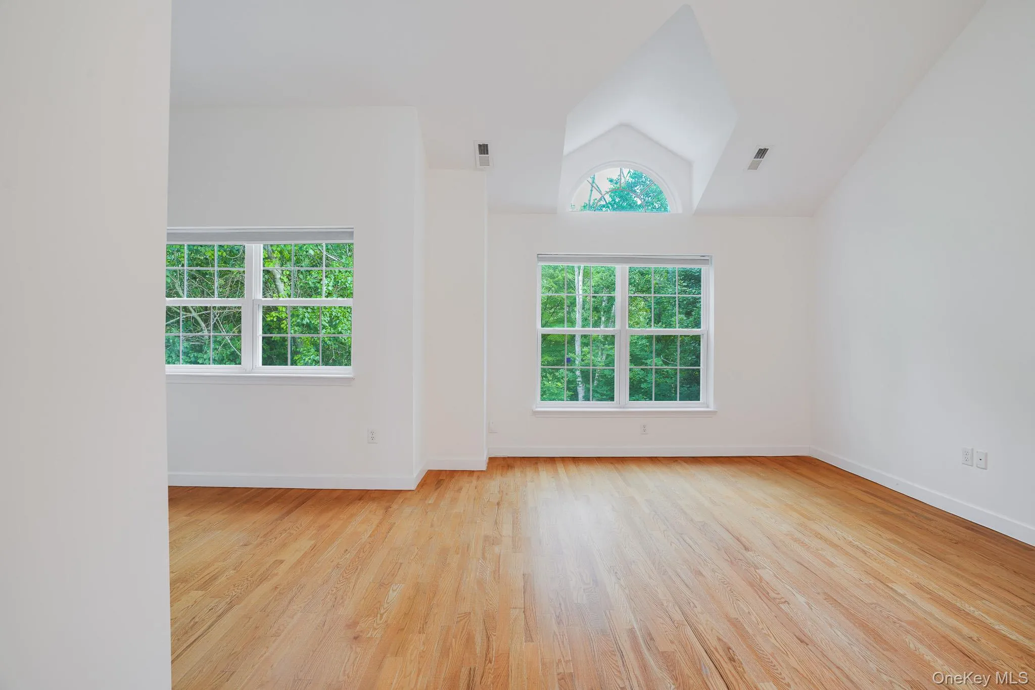 Primary bedroom with large windows overlooking peaceful wooded surroundings Primary bedroom with large windows overlooking peaceful wooded surroundings
