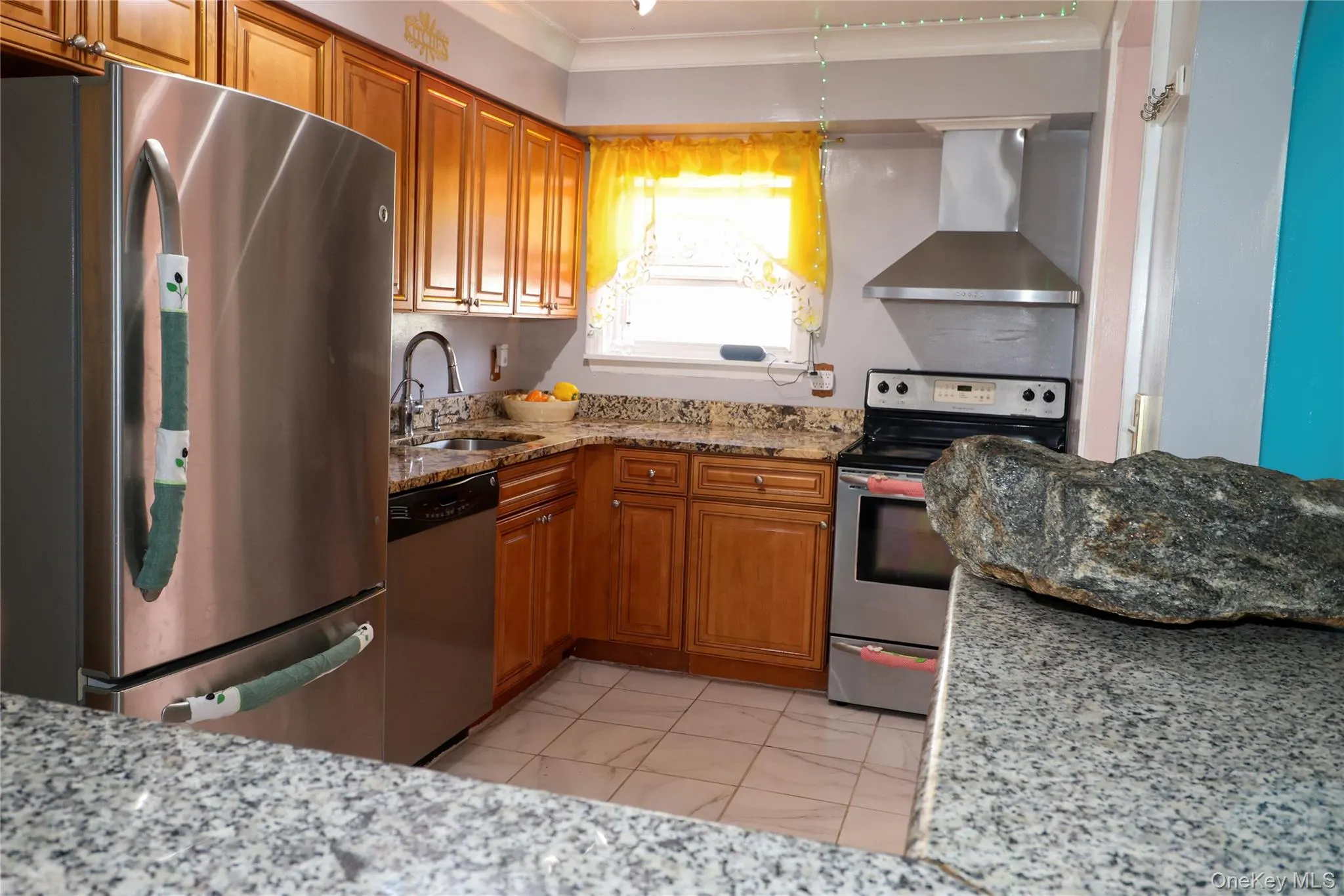Kitchen featuring wood cabinetry, stainless steel appliances, granite-style countertops, tile flooring, and a stainless steel range hood Kitchen featuring wood cabinetry, stainless steel appliances, granite-style countertops, tile flooring, and a stainless steel range hood