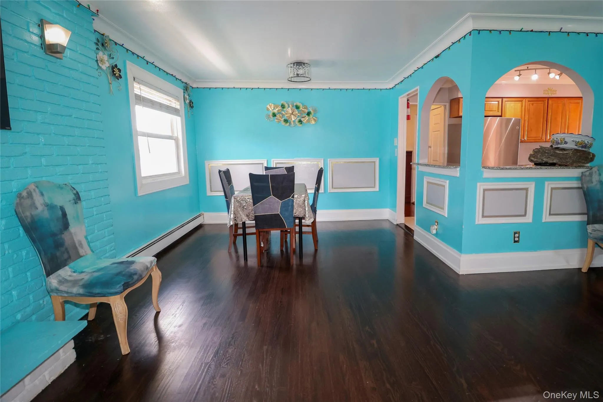 Expansive room featuring dark wood-finish flooring, white baseboards, and crown molding Expansive room featuring dark wood-finish flooring, white baseboards, and crown molding