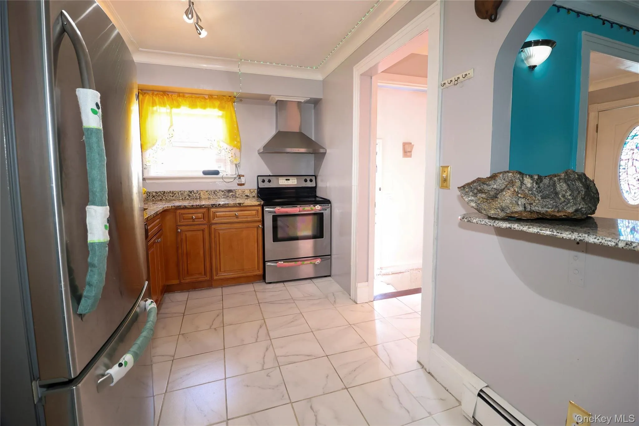 Kitchen featuring stainless steel appliances, light wood cabinetry, granite-style countertops, and a tile floor Kitchen featuring stainless steel appliances, light wood cabinetry, granite-style countertops, and a tile floor