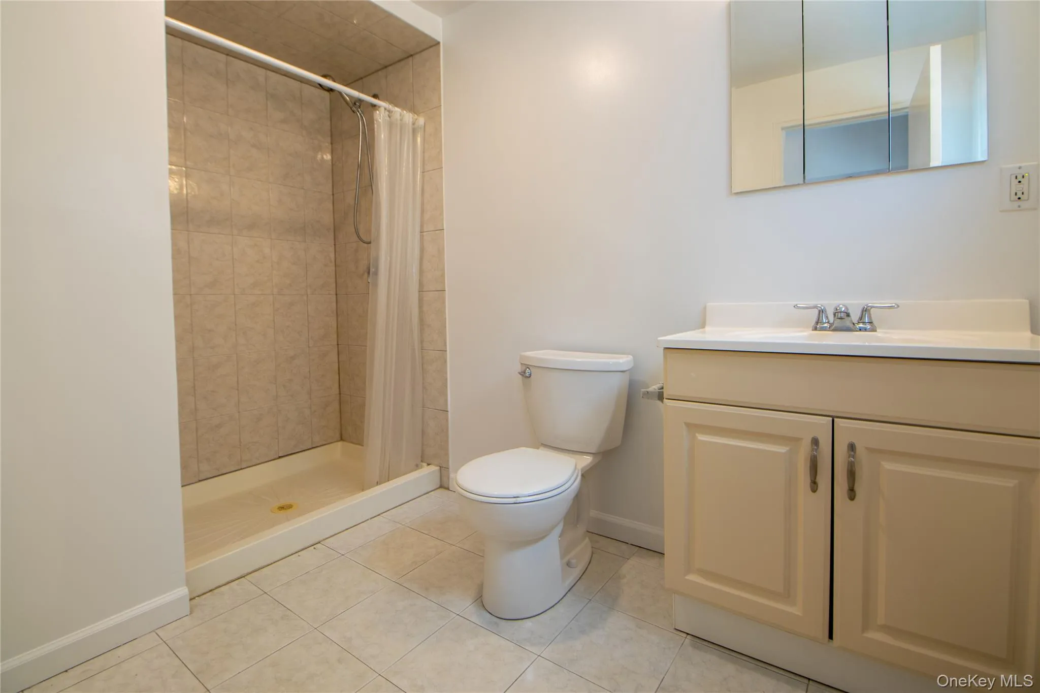 Full bathroom with toilet, tile patterned floors, baseboards, and a tile shower Full bathroom with toilet, tile patterned floors, baseboards, and a tile shower