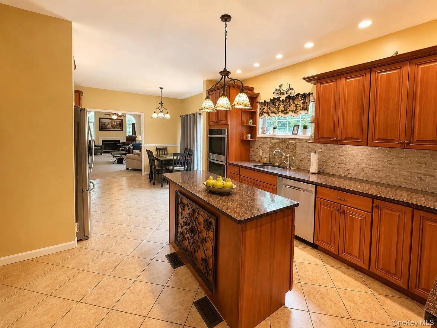Kitchen featuring an island with a decorative panel, recessed lighting, tile flooring, wood cabinetry, and a tile backsplash Kitchen featuring an island with a decorative panel, recessed lighting, tile flooring, wood cabinetry, and a tile backsplash