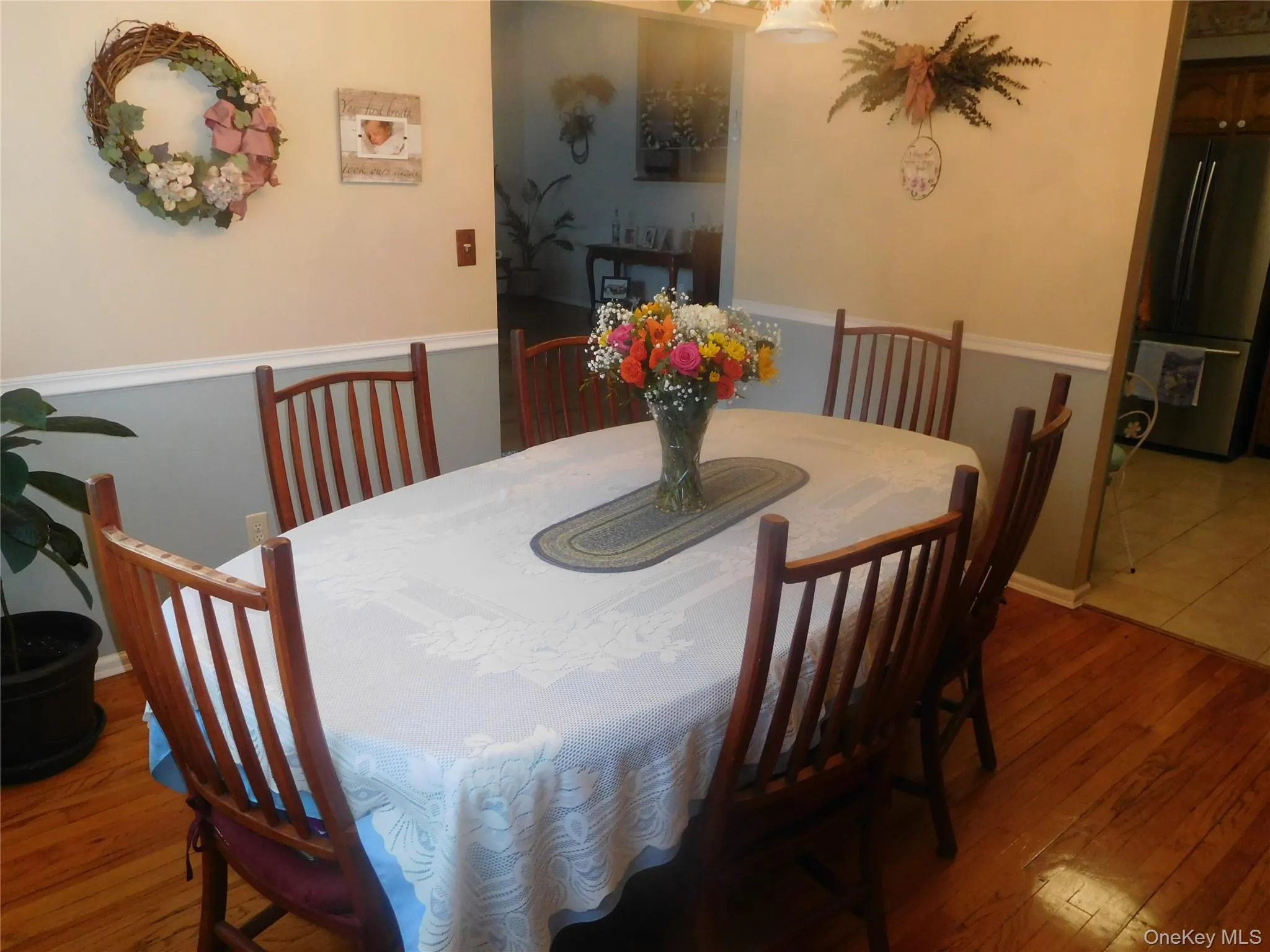 Dining area with wood-finish flooring, two-tone wall paint, and a decorative ceiling light fixture Dining area with wood-finish flooring, two-tone wall paint, and a decorative ceiling light fixture