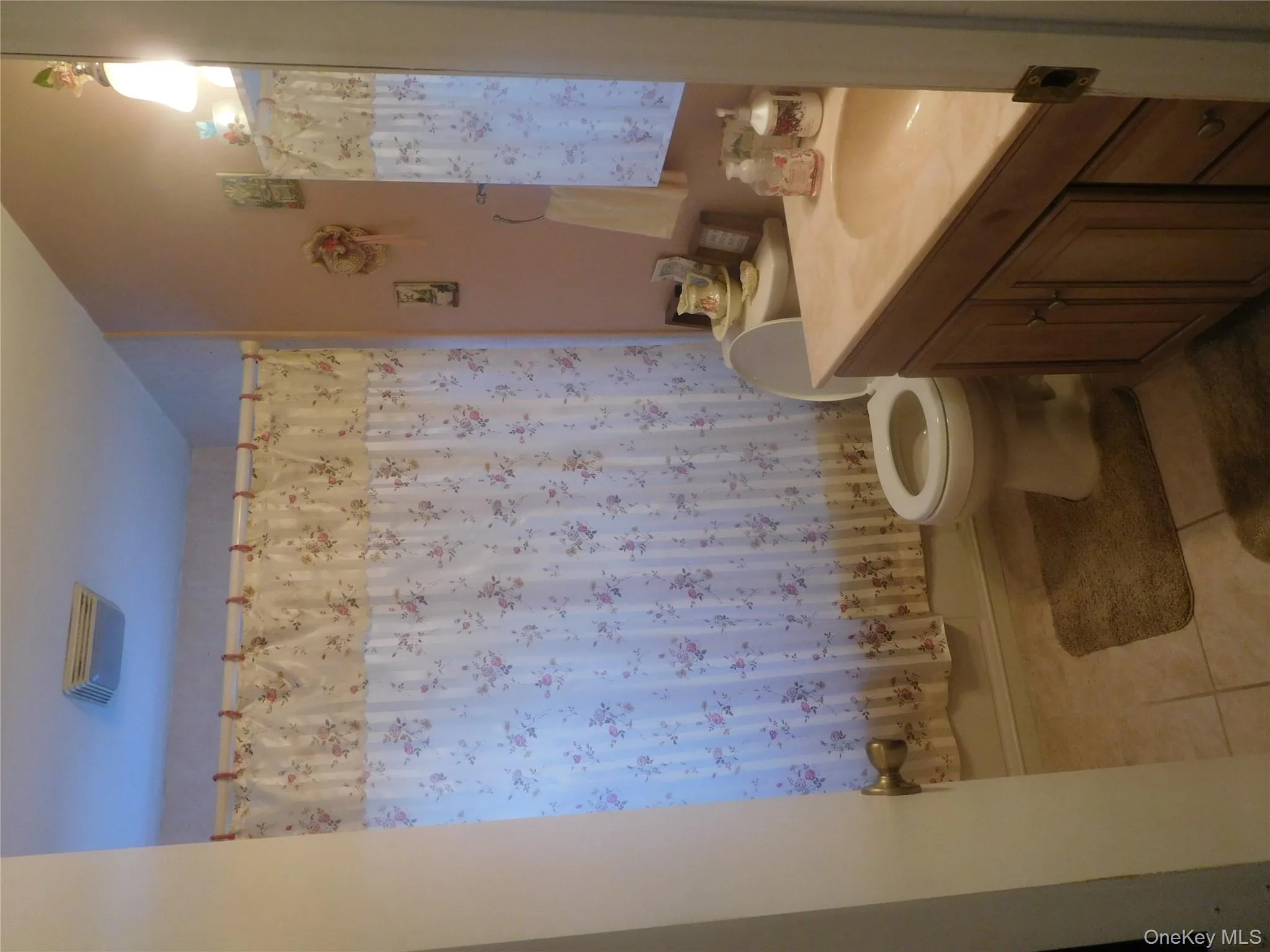 Bathroom featuring a light wood-finish vanity with an integrated countertop sink, a white toilet, and tiled flooring Bathroom featuring a light wood-finish vanity with an integrated countertop sink, a white toilet, and tiled flooring