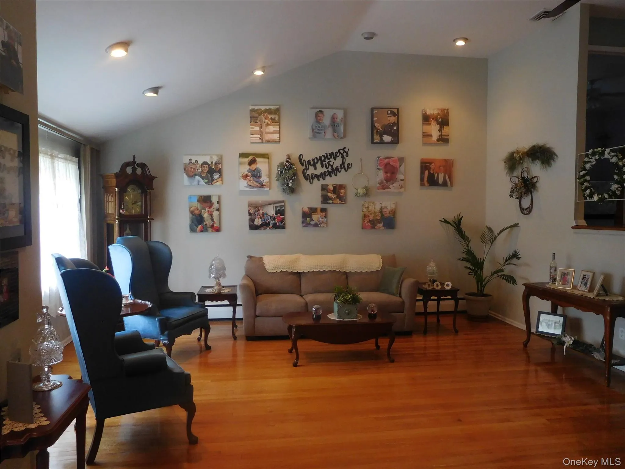 Spacious living area featuring polished wood flooring, a vaulted ceiling, recessed lighting, and ample wall space Spacious living area featuring polished wood flooring, a vaulted ceiling, recessed lighting, and ample wall space