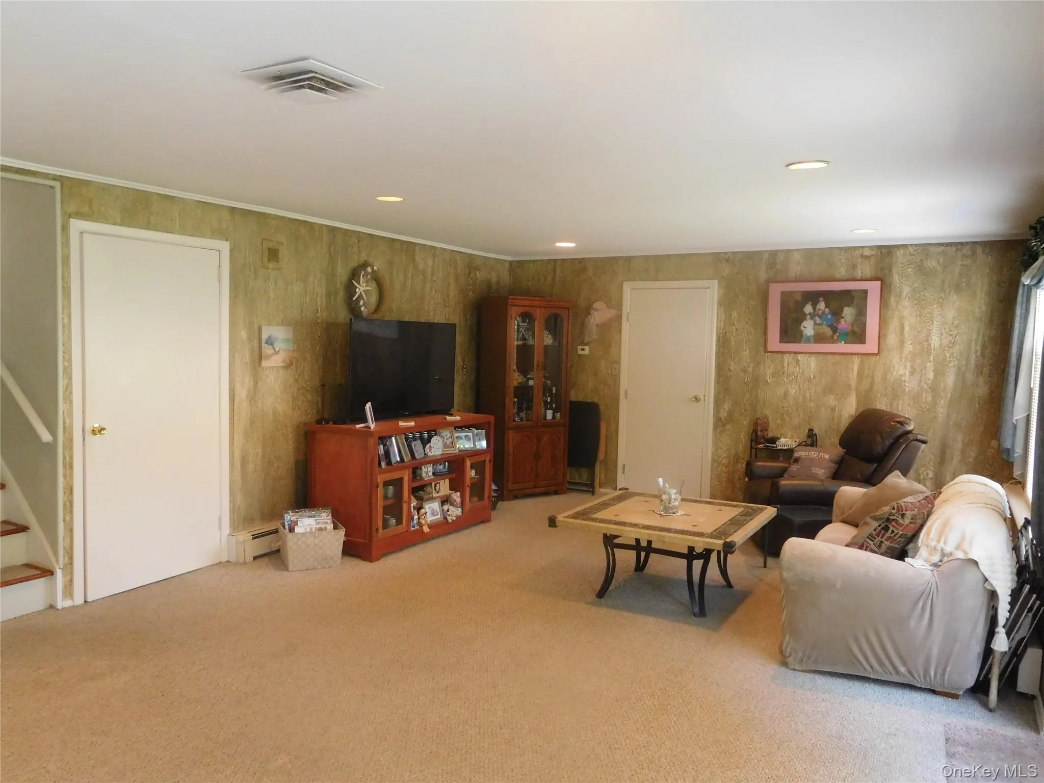 Carpeted living area featuring textured wall finish, white trim, recessed lighting, and a white ceiling with a central air vent Carpeted living area featuring textured wall finish, white trim, recessed lighting, and a white ceiling with a central air vent
