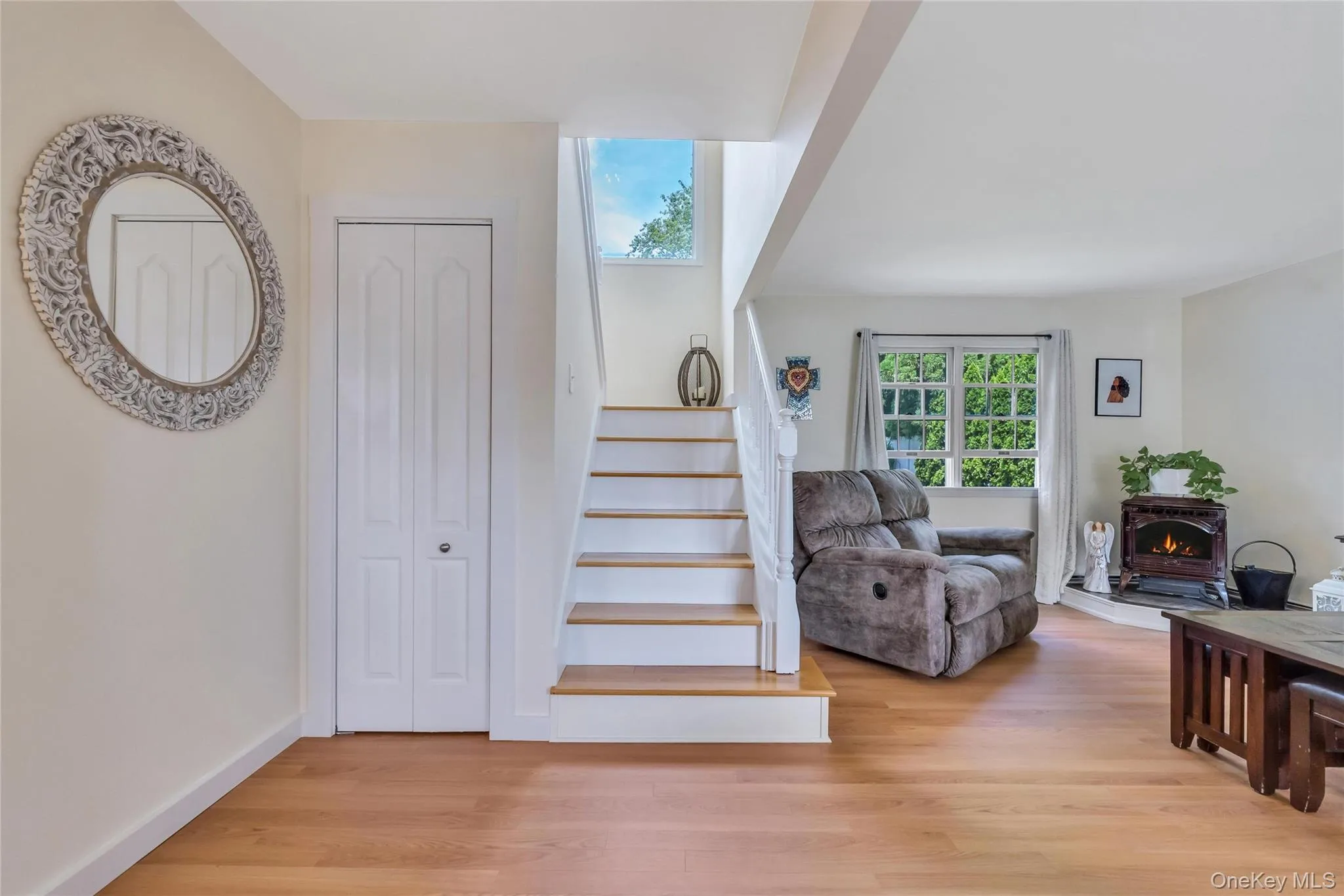 Entryway featuring new flooring, white bi-fold closet doors, and a staircase with wood treads and white risers Entryway featuring new flooring, white bi-fold closet doors, and a staircase with wood treads and white risers