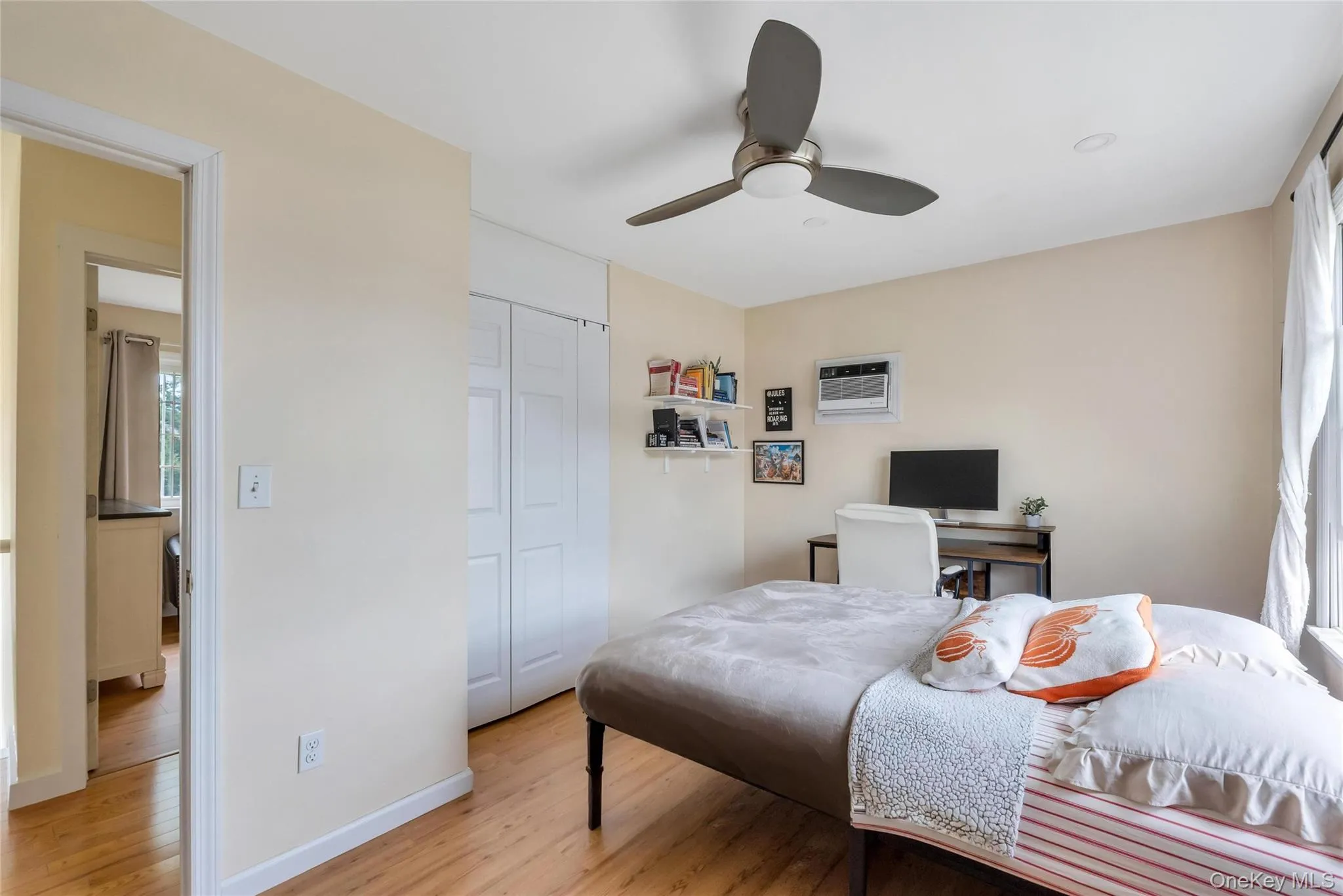 Bedroom featuring wood-finish flooring, a ceiling fan with integrated lighting, recessed lighting, a built-in closet with bi-fold doors, and a window with white curtains Bedroom featuring wood-finish flooring, a ceiling fan with integrated lighting, recessed lighting, a built-in closet with bi-fold doors, and a window with white curtains