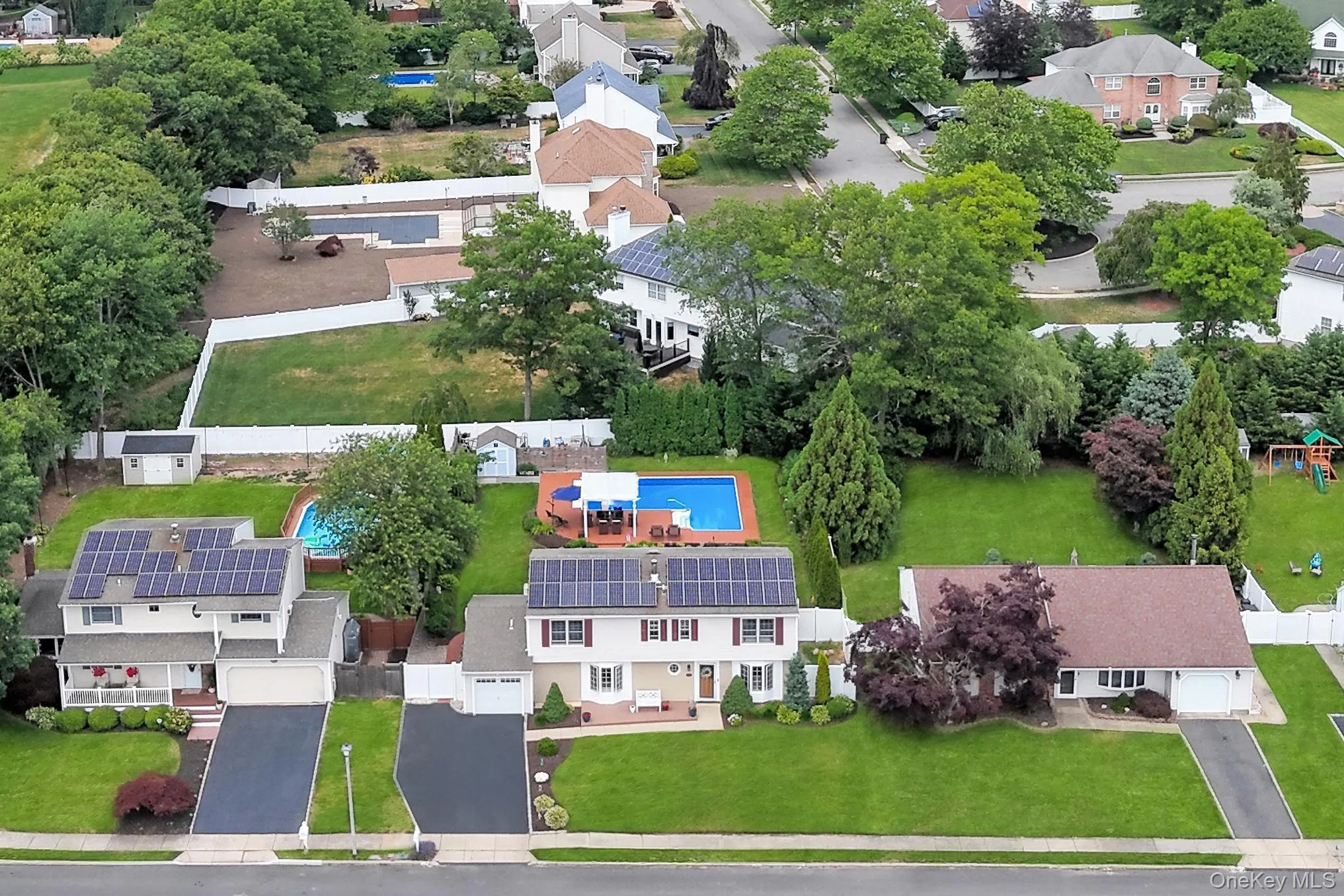 Aerial perspective showcasing multiple properties, each featuring a private swimming pool, mature landscaping, and solar panel installations Aerial perspective showcasing multiple properties, each featuring a private swimming pool, mature landscaping, and solar panel installations