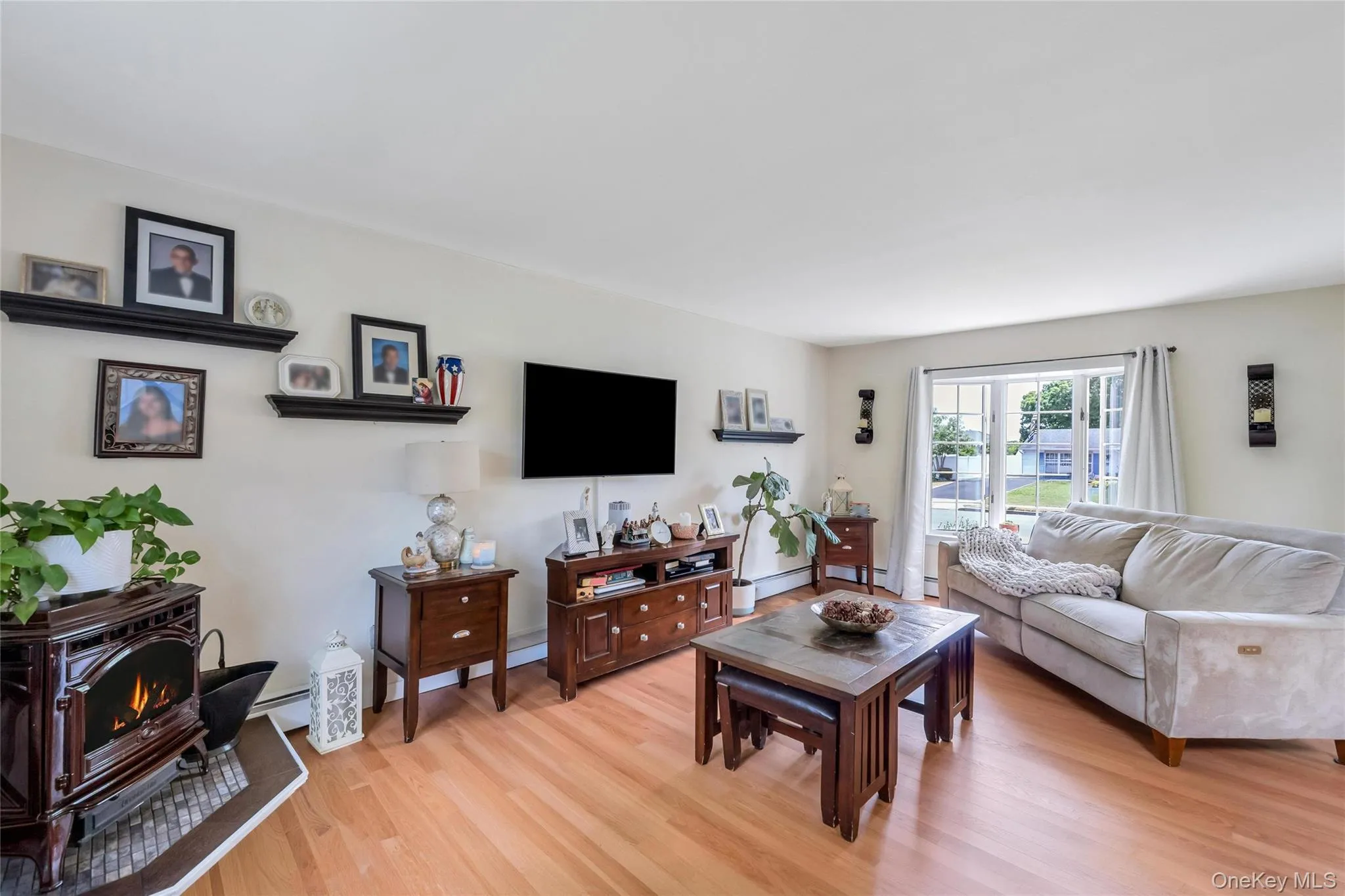 Living area featuring wood-finish flooring, a large window, and light-toned walls Living area featuring wood-finish flooring, a large window, and light-toned walls