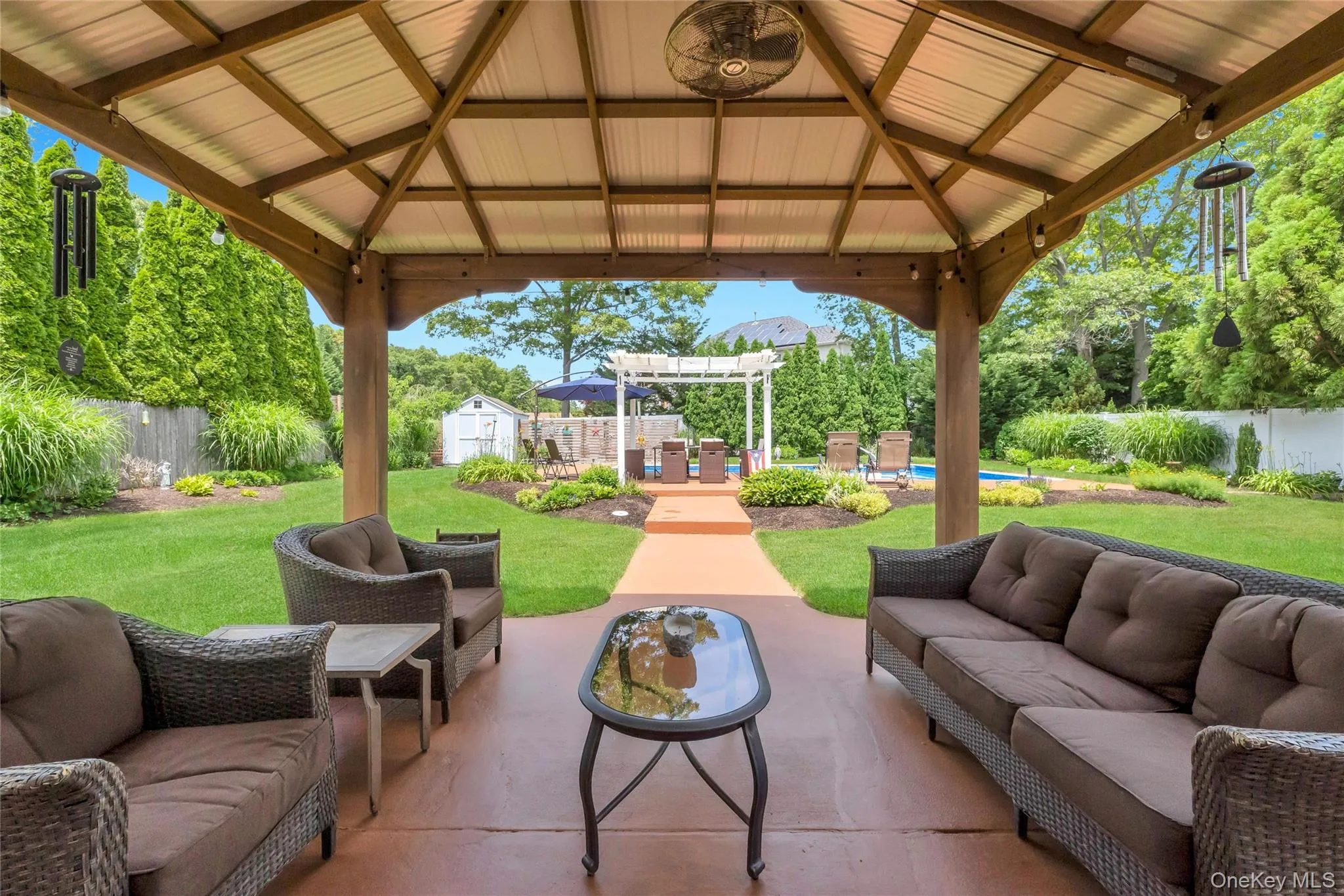 Expansive backyard featuring a covered patio, manicured lawn, and mature privacy plantings Expansive backyard featuring a covered patio, manicured lawn, and mature privacy plantings