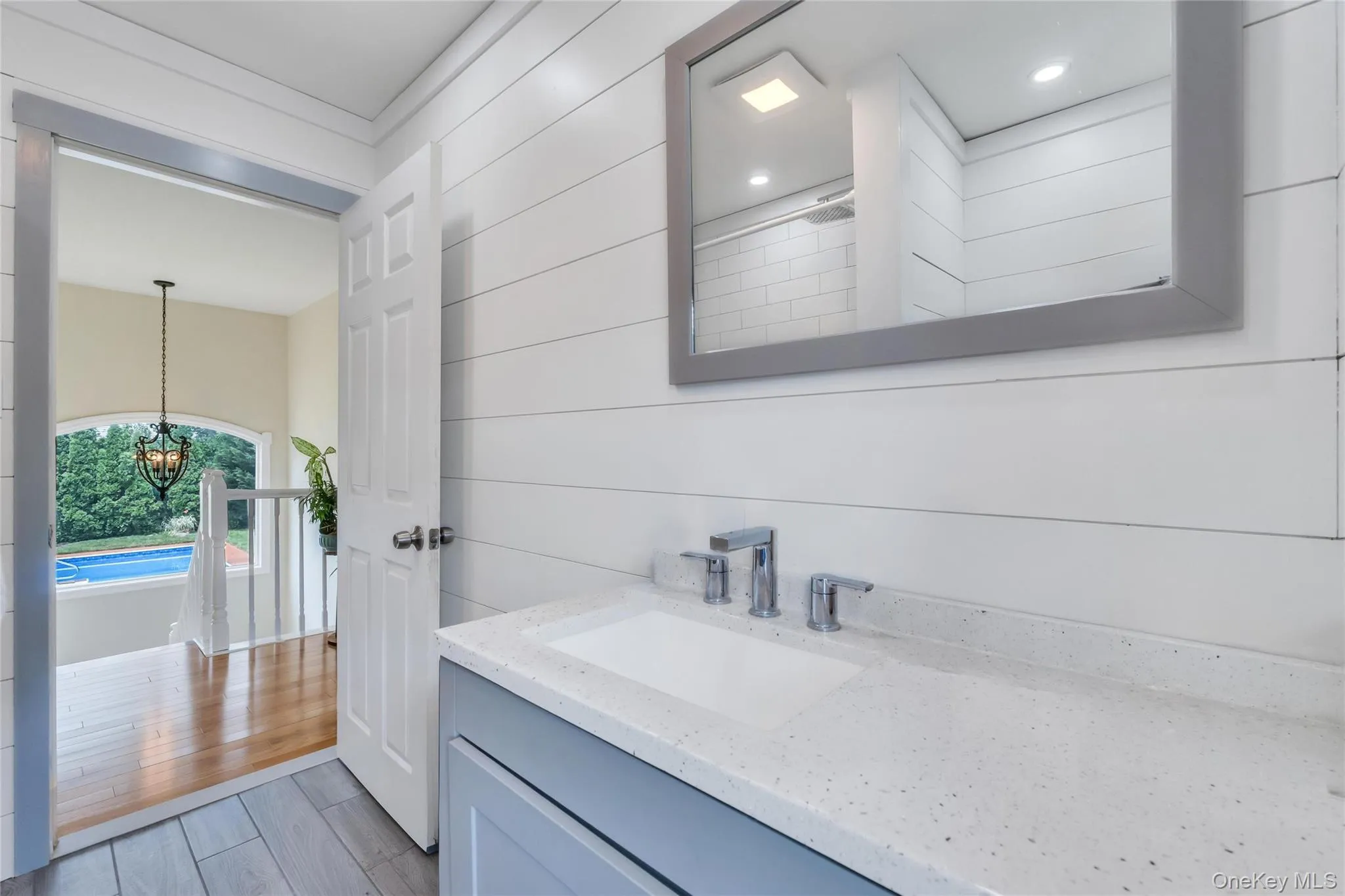 Bathroom vanity featuring a light gray cabinet, white countertop with integrated sink, and brushed chrome fixtures Bathroom vanity featuring a light gray cabinet, white countertop with integrated sink, and brushed chrome fixtures