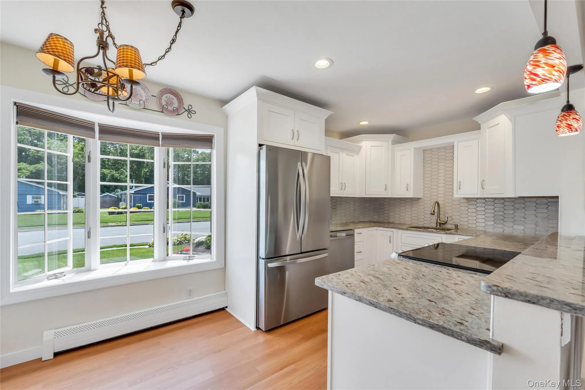 Kitchen featuring white cabinetry, stainless steel appliances, speckled stone countertops, and a subway tile backsplash Kitchen featuring white cabinetry, stainless steel appliances, speckled stone countertops, and a subway tile backsplash